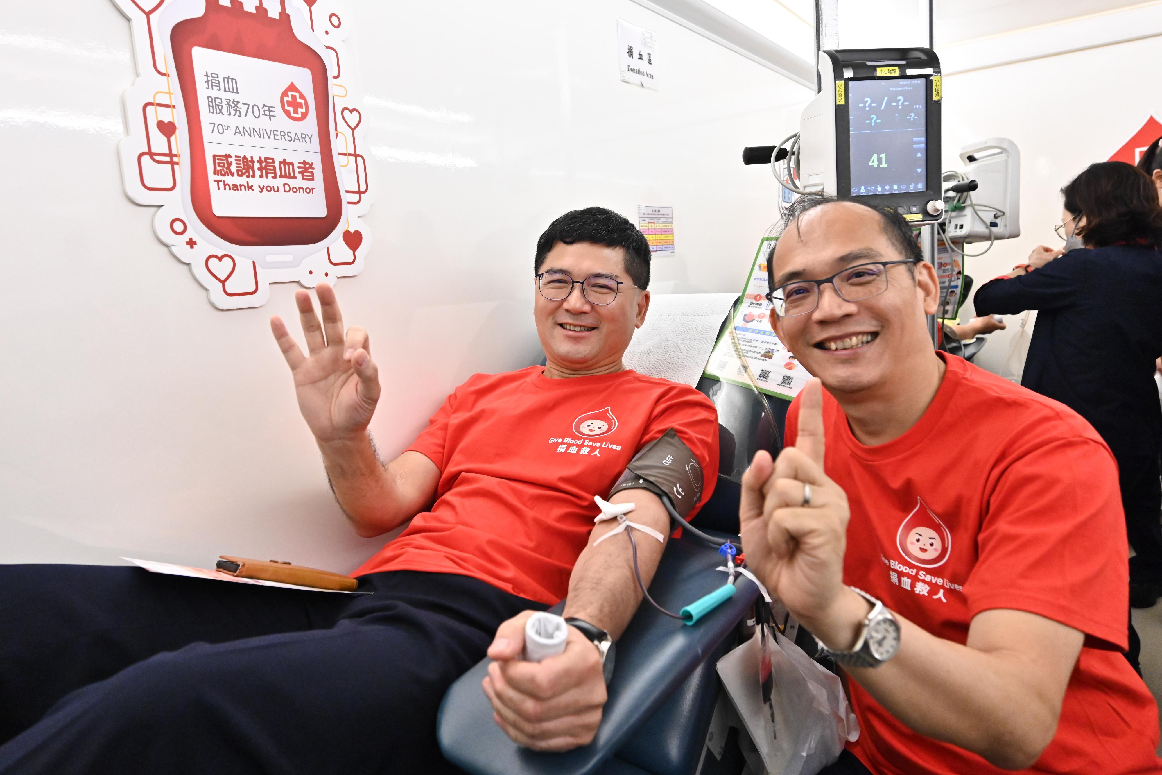 The Chief Executive of the Hospital Authority, Dr Tony Ko (left), donates blood on the mobile blood donation vehicle of the Hong Kong Red Cross Blood Transfusion Service parked at the Central Government Offices today (August 14).