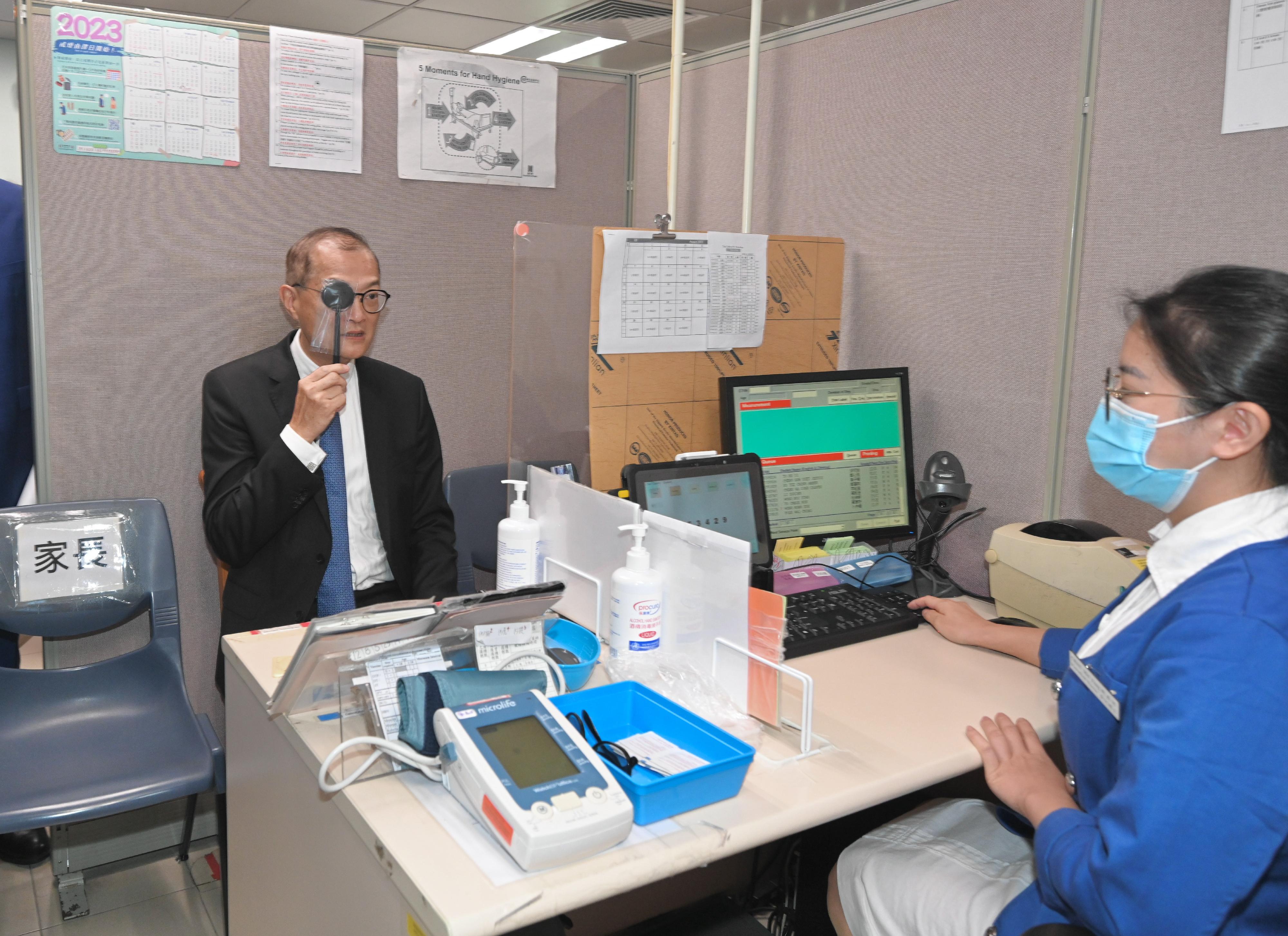 The Secretary for Health, Professor Lo Chung-mau, visited the Lam Tin Student Health Service Centre under the Department of Health this afternoon (August 15). Photo shows Professor Lo (left) taking part in an eye test at the Centre.
