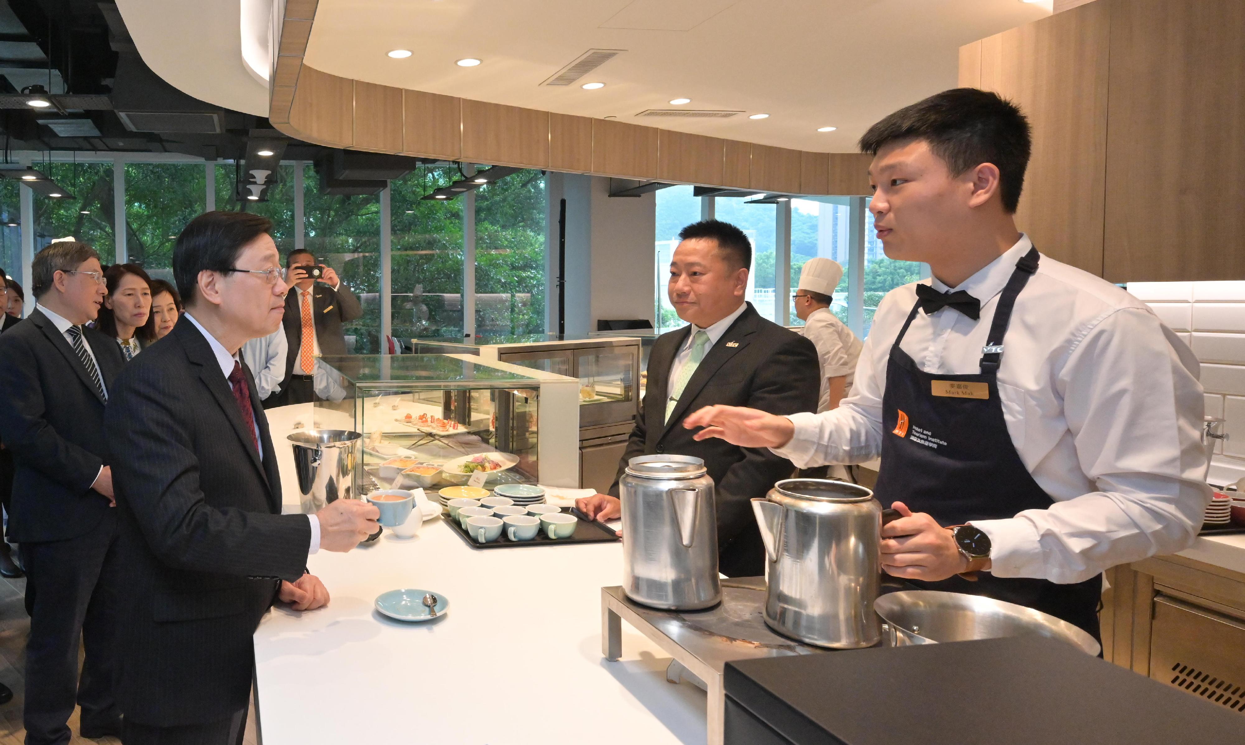 行政長官李家超今日（八月十七日）到訪職業訓練局轄下的國際廚藝學院。圖示李家超（前排左一）品嚐由學員沖泡的奶茶。