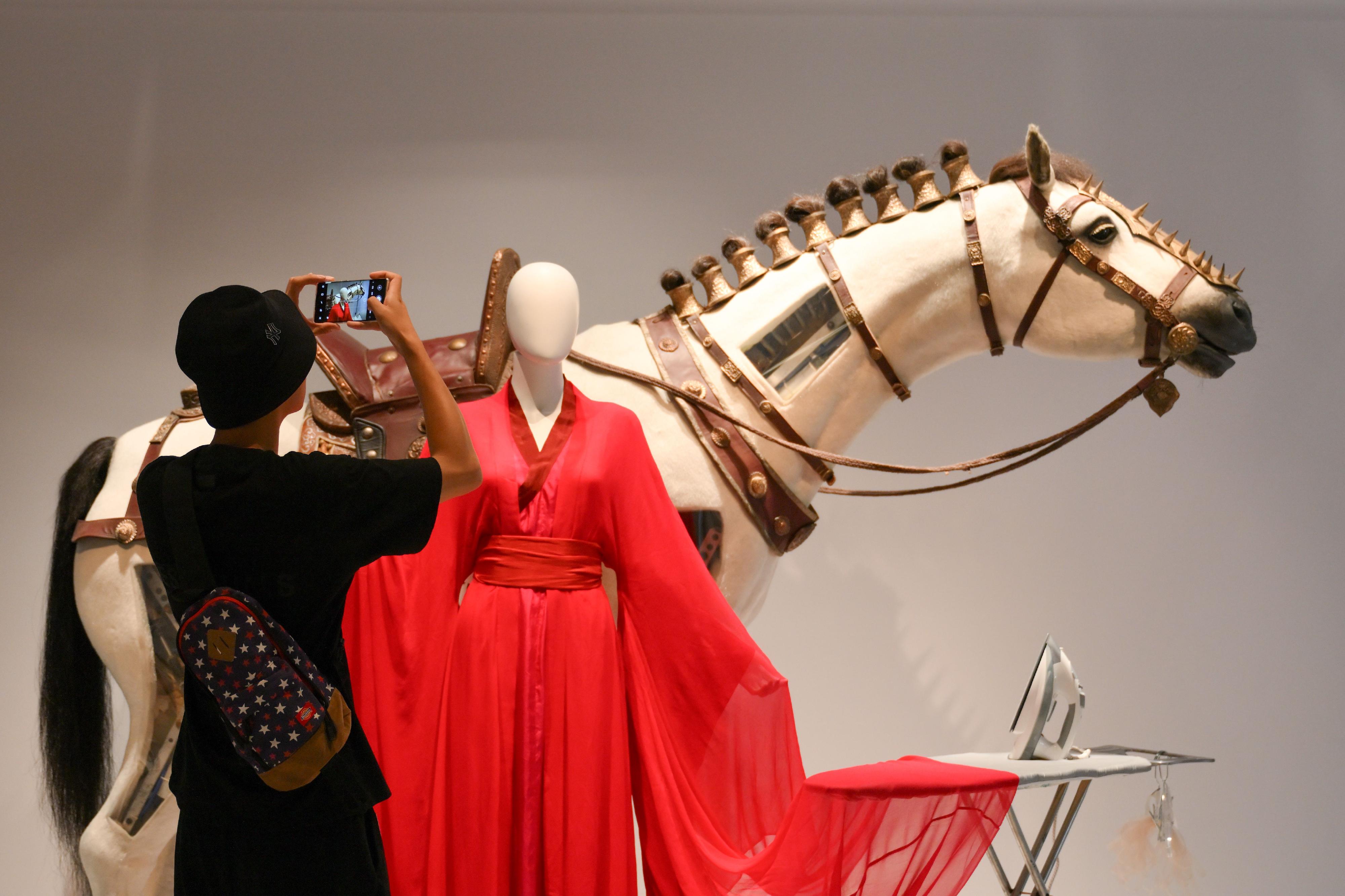 现正于香港文化博物馆举行的「无中生有——香港电影美术及服装造型展」将于九月四日 （星期一）结束，市民请把握机会在余下展期前往参观。图示参观者正观赏张曼玉于《英雄》（2002）中穿着的红色古装和《狄仁杰之神刀龙王》（2013）中的特别道具「水中马」。