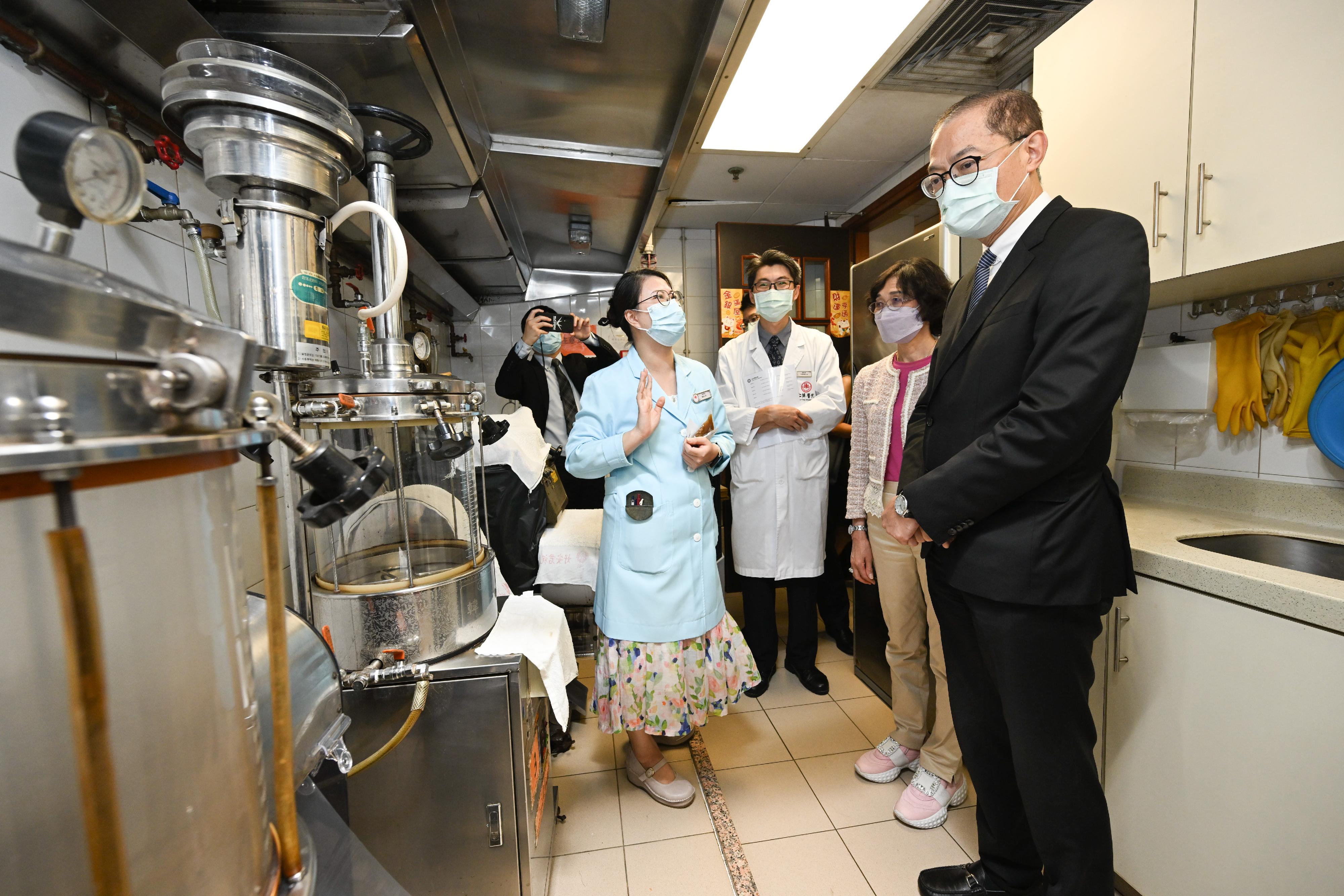 The Secretary for Health, Professor Lo Chung-mau (first right), listens to the introduction by a staff member on the facilities of the Chinese medicine dispensary during his visit to the Chinese Medicine Clinic cum Training and Research Centre in Kwai Tsing District today (August 29).