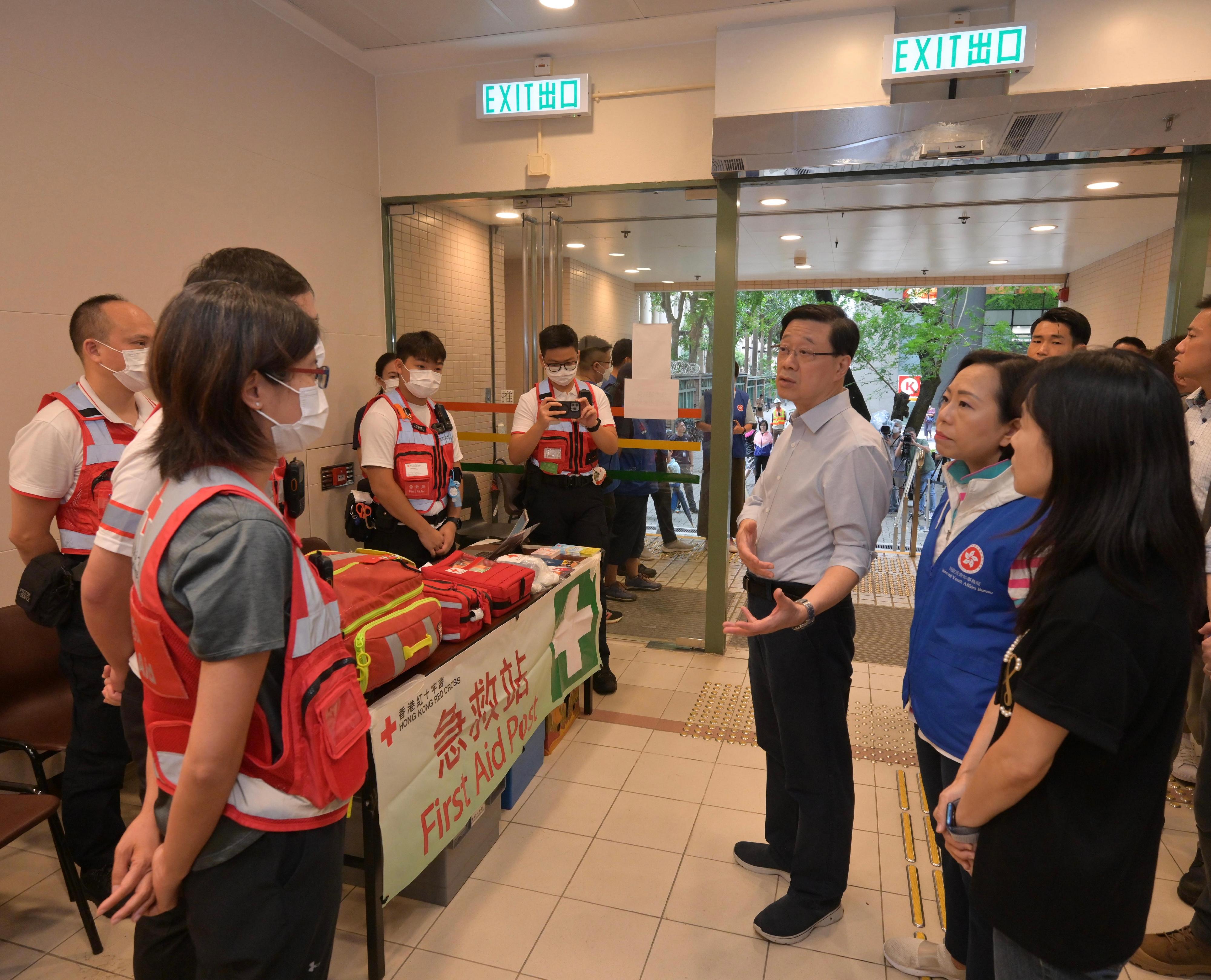The Chief Executive, Mr John Lee, inspected the relief work in the wake of the torrential rain in Fanling today (September 9). Photo shows Mr Lee (third right), accompanied by the Secretary for Home and Youth Affairs, Miss Alice Mak (second right), chatting with staff at the temporary shelter in Luen Wo Hui Community Hall.