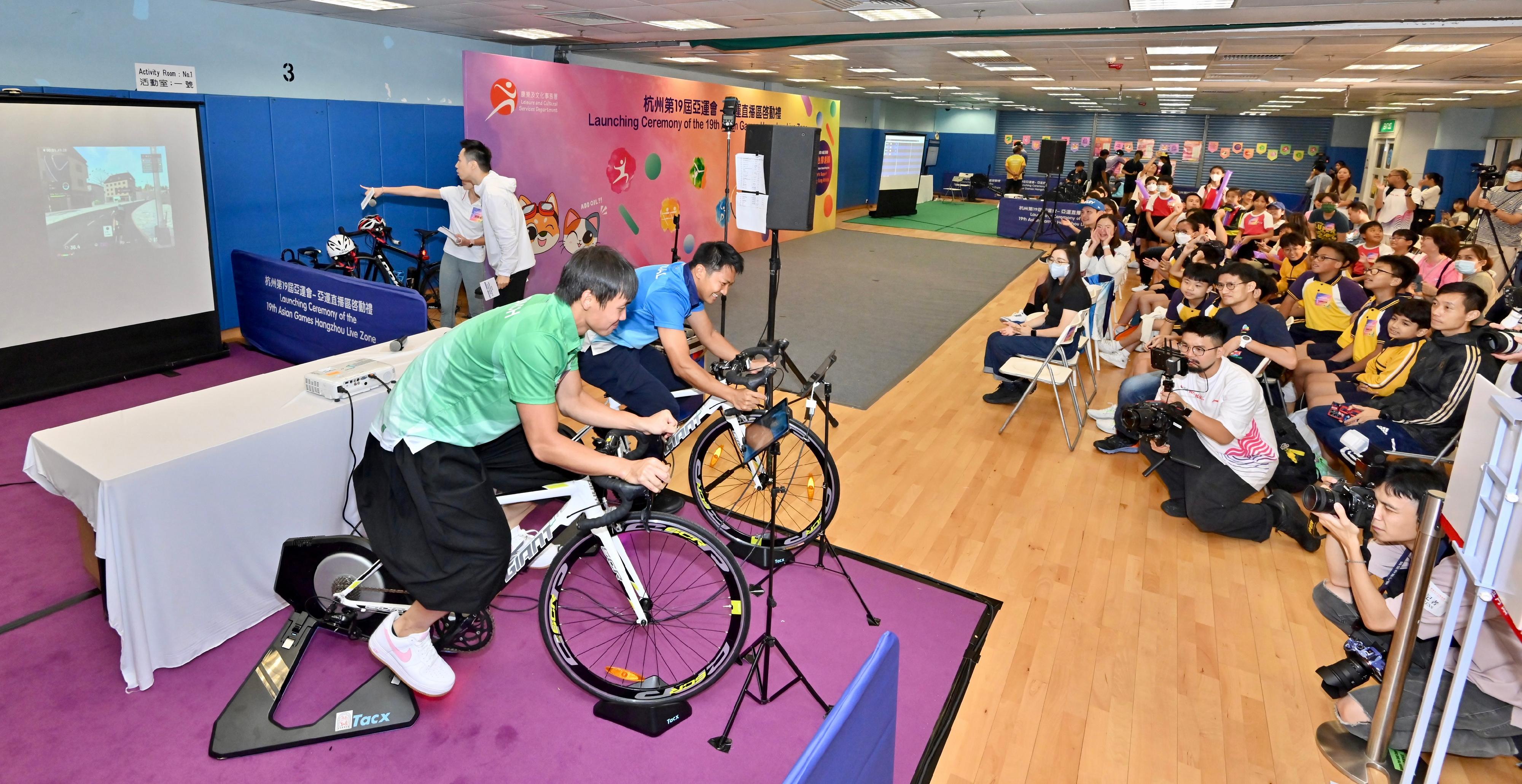The Leisure and Cultural Services Department held the "Launching Ceremony of the 19th Asian Games Hangzhou Live Zone" at the Secondary Hall of the Kowloon Park Sports Centre today (September 23). Photo shows former cycling athlete Leung Chi-yin (second left) and Chau Dor-ming (first left) demonstrating sports skills to the audience.