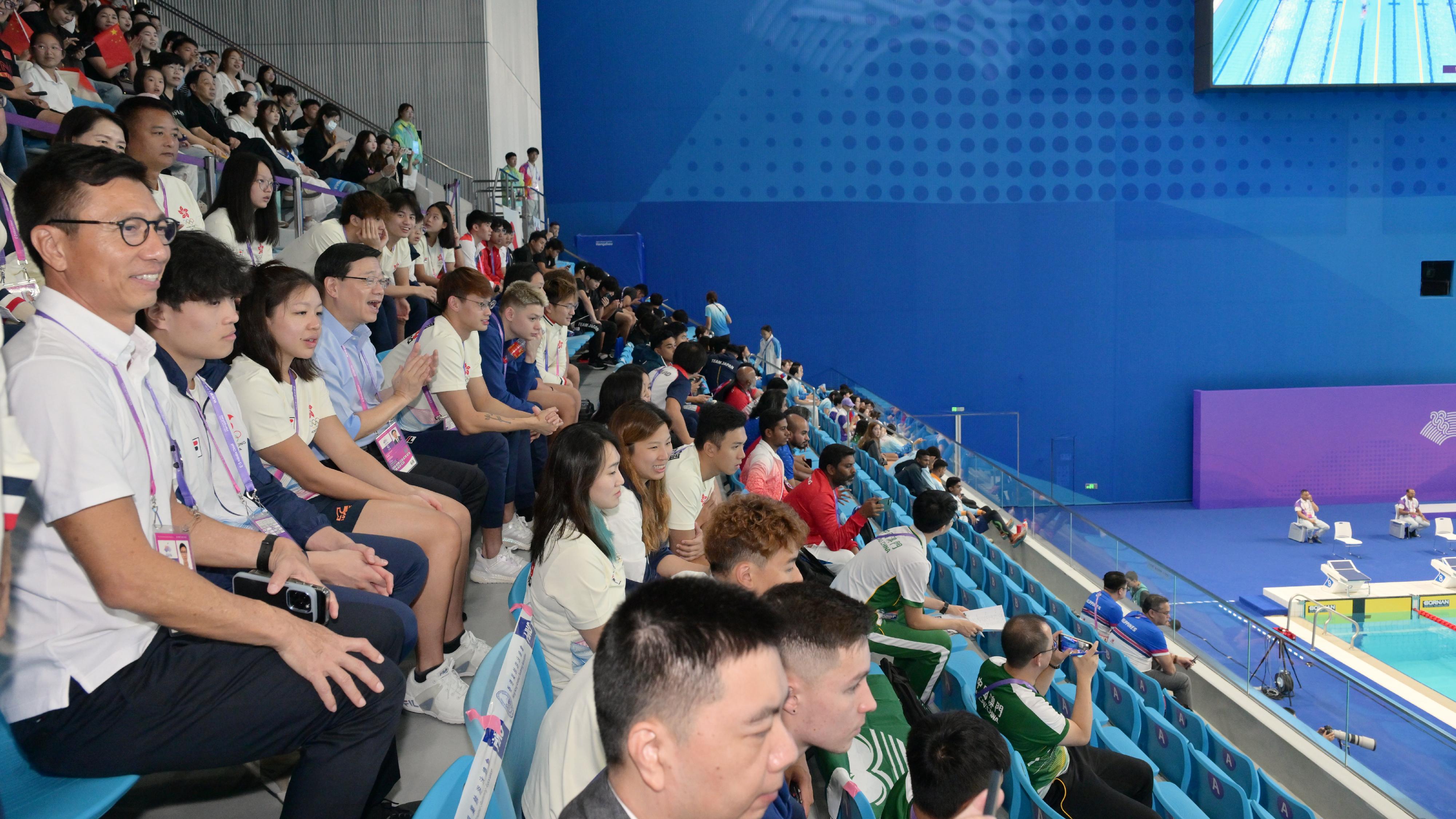 行政长官李家超今日（九月二十四日）率领香港特别行政区政府代表团继续其杭州访问行程。图示李家超（左四）在文化体育及旅游局体育专员黄德森（左一）陪同下，与香港运动员观看游泳赛事。