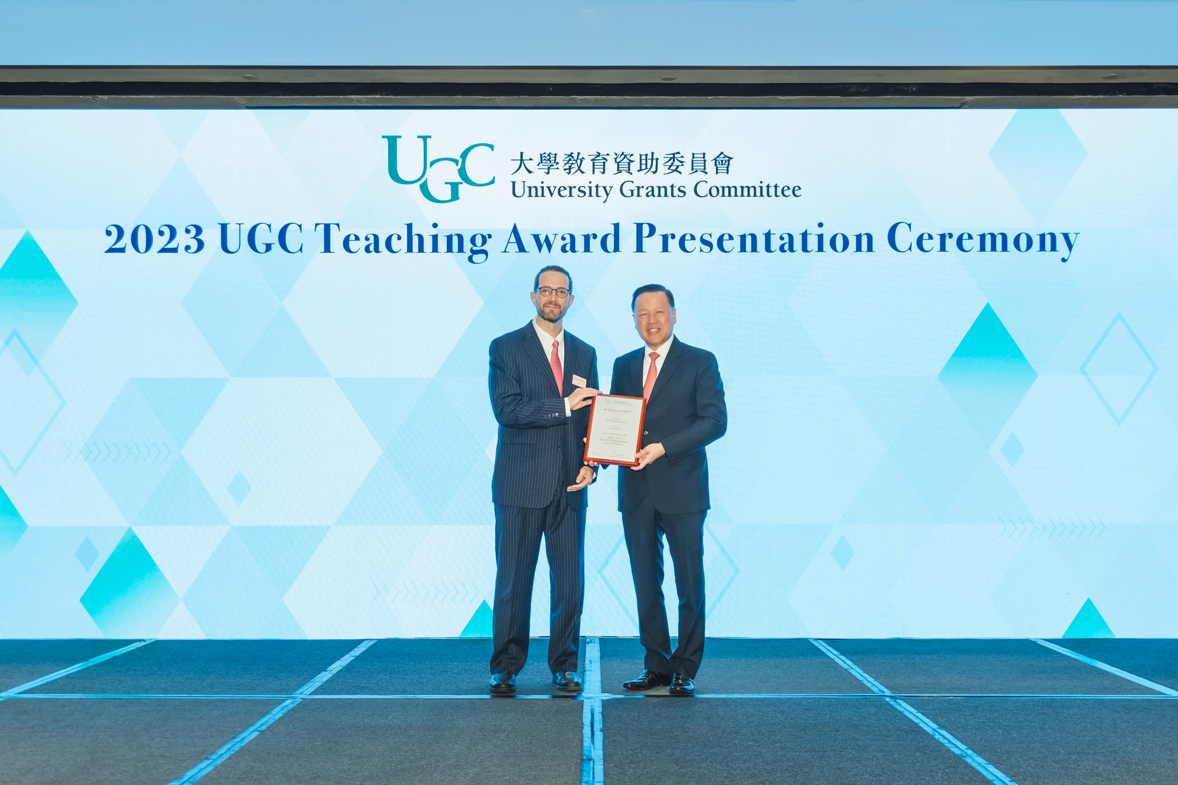 The Chairman of the University Grants Committee (UGC), Mr Tim Lui (right), today (September 27) presents the 2023 UGC Teaching Award for General Faculty Members to Mr David Lorin Bishop (left) of the University of Hong Kong.