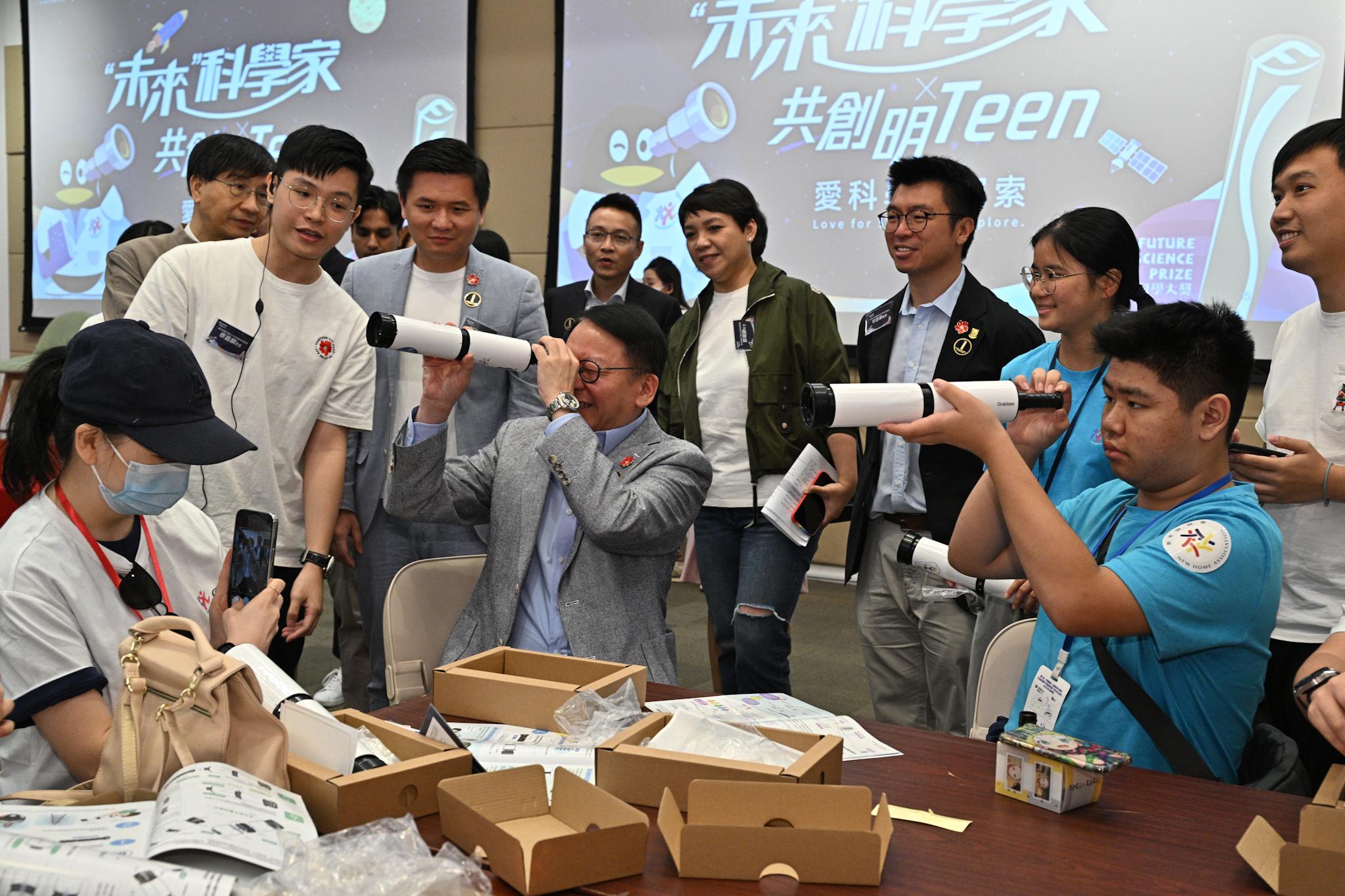 政務司司長陳國基今日（九月三十日）出席「共創明『Teen』計劃」──「未來」科學家．愛科學．i探索活動。圖示陳國基（前排中）了解學員拼裝的望遠鏡。 