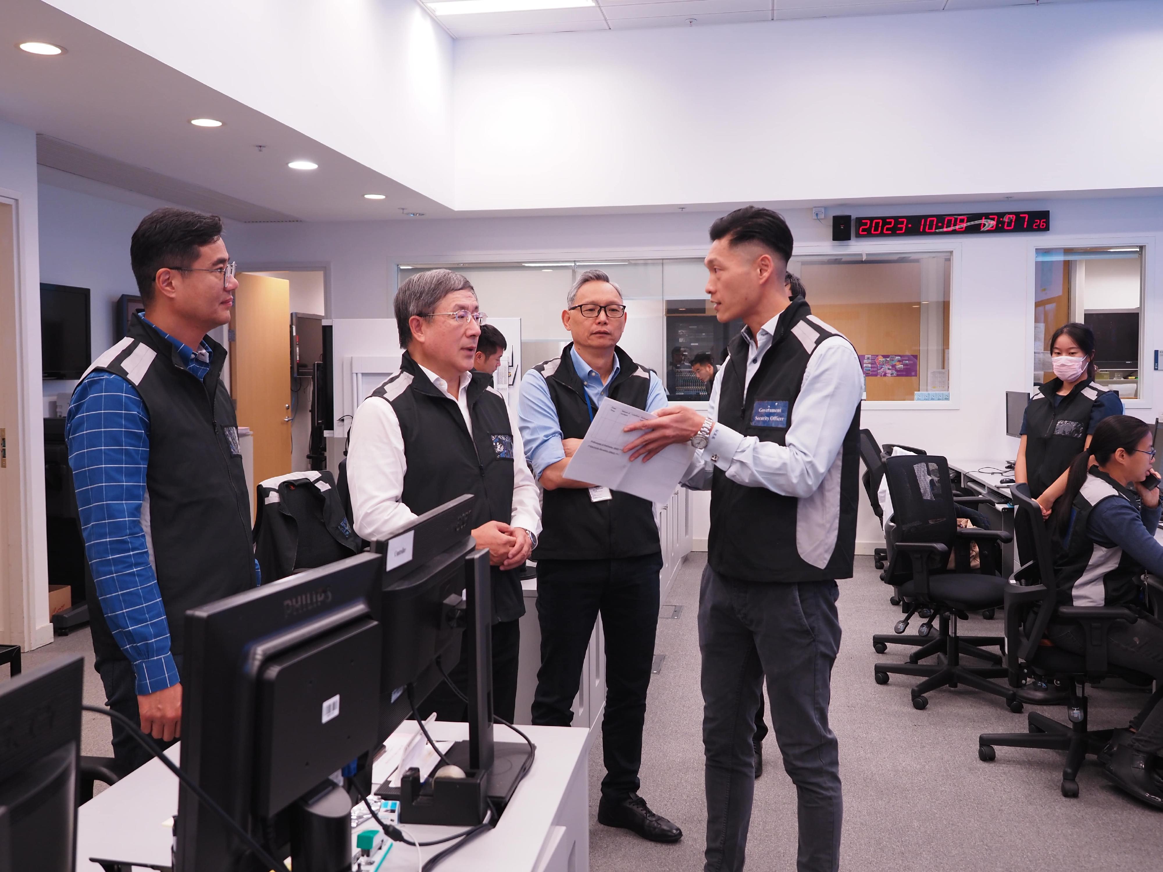 The Acting Chief Secretary for Administration, Mr Cheuk Wing-hing (second left), is being briefed by colleagues of the Security Bureau at the Emergency Monitoring and Support Centre today (October 8).