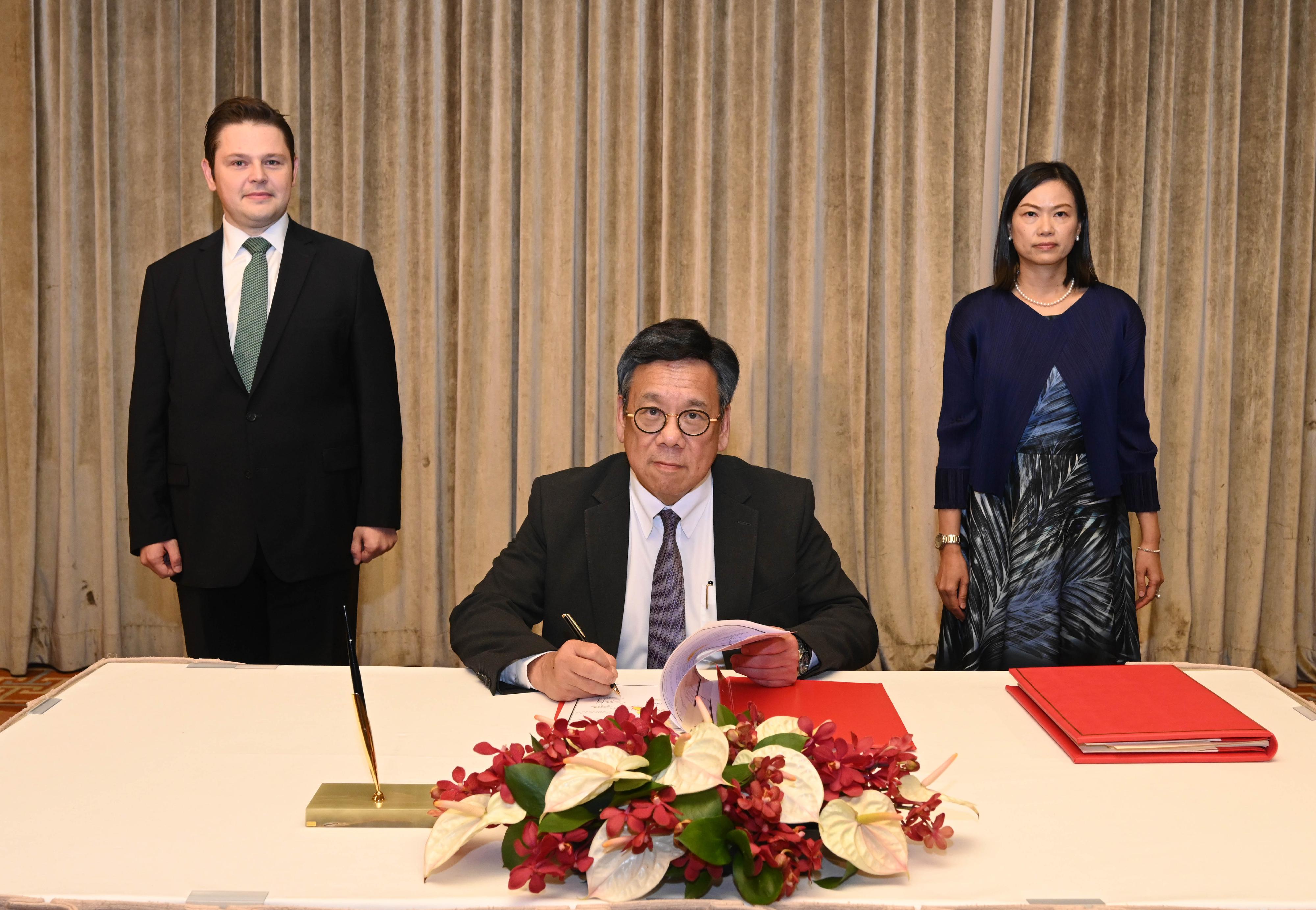 The Secretary for Commerce and Economic Development, Mr Algernon Yau (front), witnessed by the Consul General of Türkiye in Hong Kong, Mr Kerim Sercan Evcin (left, back row), and accompanied by the Director-General of Trade and Industry, Ms Maggie Wong (right, back row), signs the Hong Kong-Türkiye Investment Promotion and Protection Agreement today (October 31).