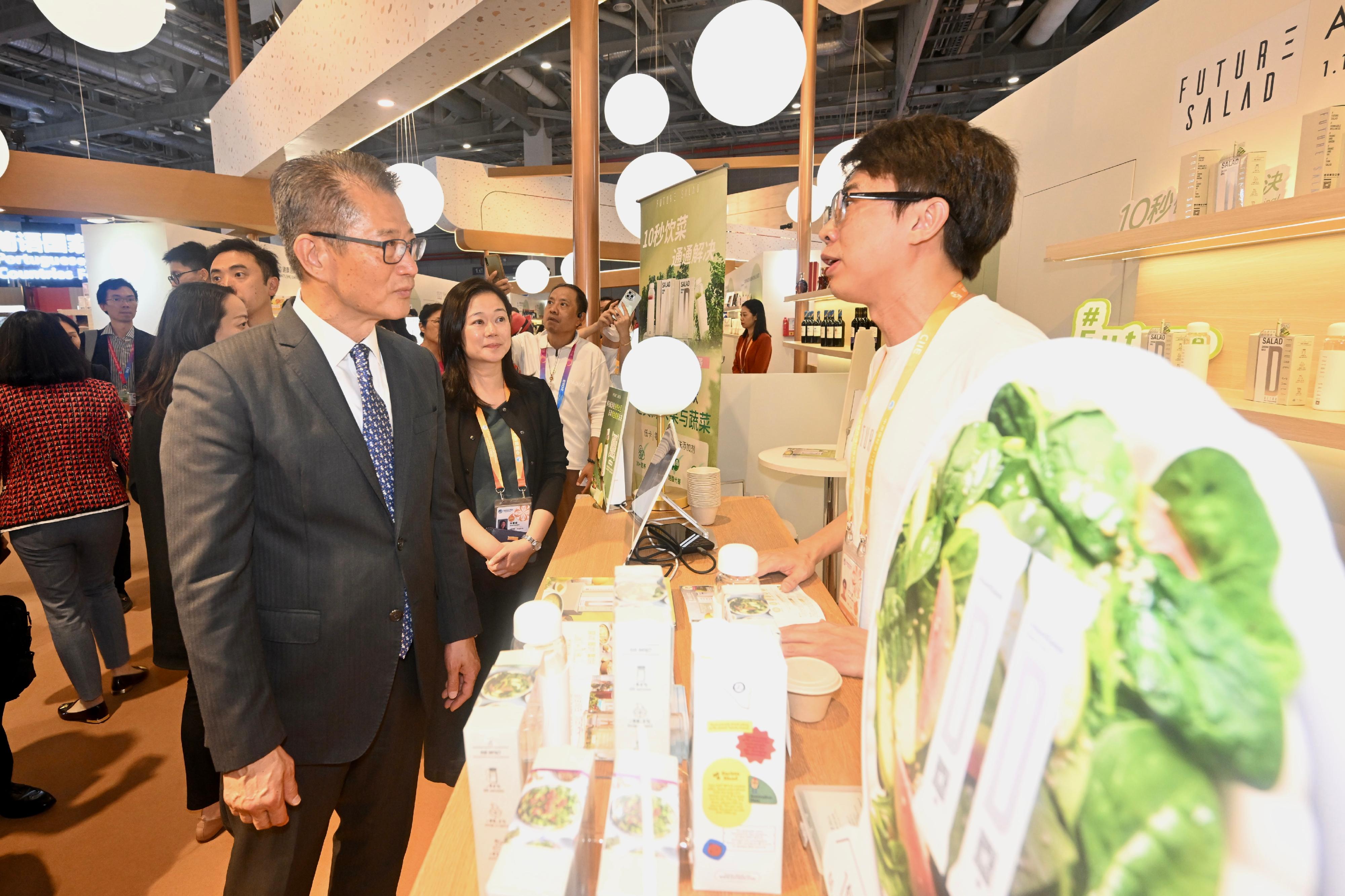 財政司司長陳茂波今日（十一月五日）在上海舉行的第六屆中國國際進口博覽會到訪香港的參展商展位。圖示陳茂波（左一）聽取參展商介紹其產品。
