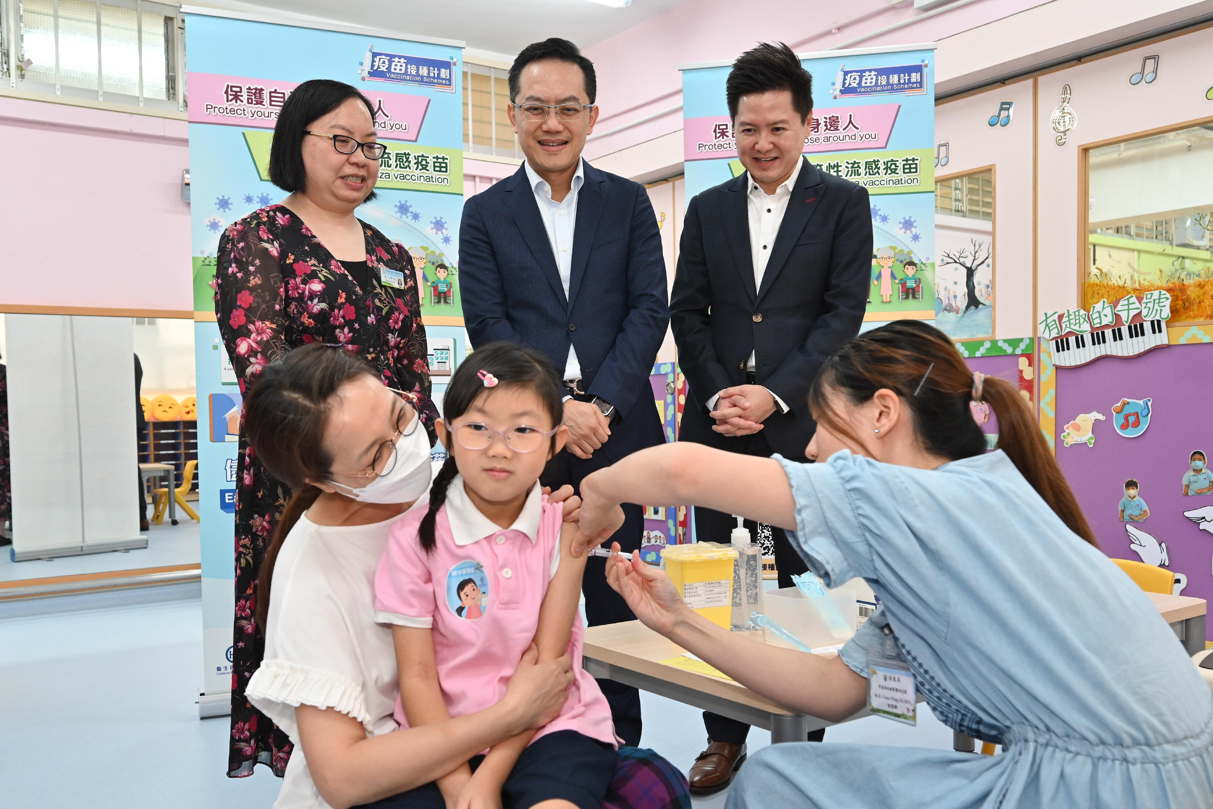 The Director of Health, Dr Ronald Lam, and the Controller of the Centre for Health Protection of the Department of Health, Dr Edwin Tsui, visited Po Leung Kuk Lee Siu Chan Kindergarten-Cum-Nursery in Kwun Tong this morning (November 9) to view the implementation of the school outreach seasonal influenza vaccination service. Photo shows Dr Lam (back row, centre) and Dr Tsui (back row, right) viewing a student receiving seasonal influenza vaccination.