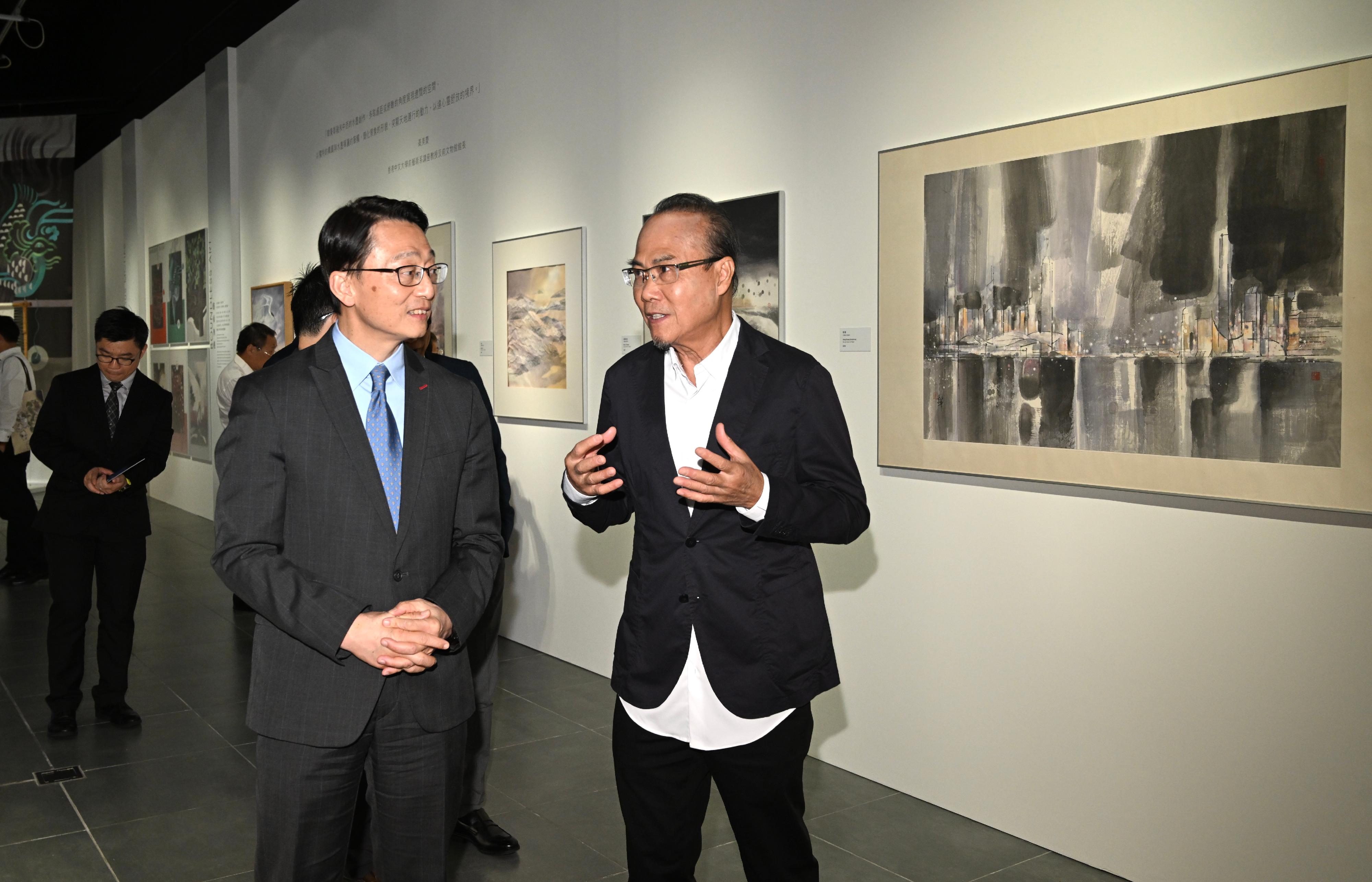 設計師及藝術家韓秉華教授（右）向主禮嘉賓康樂及文化事務署署長劉明光（左）介紹展覽。