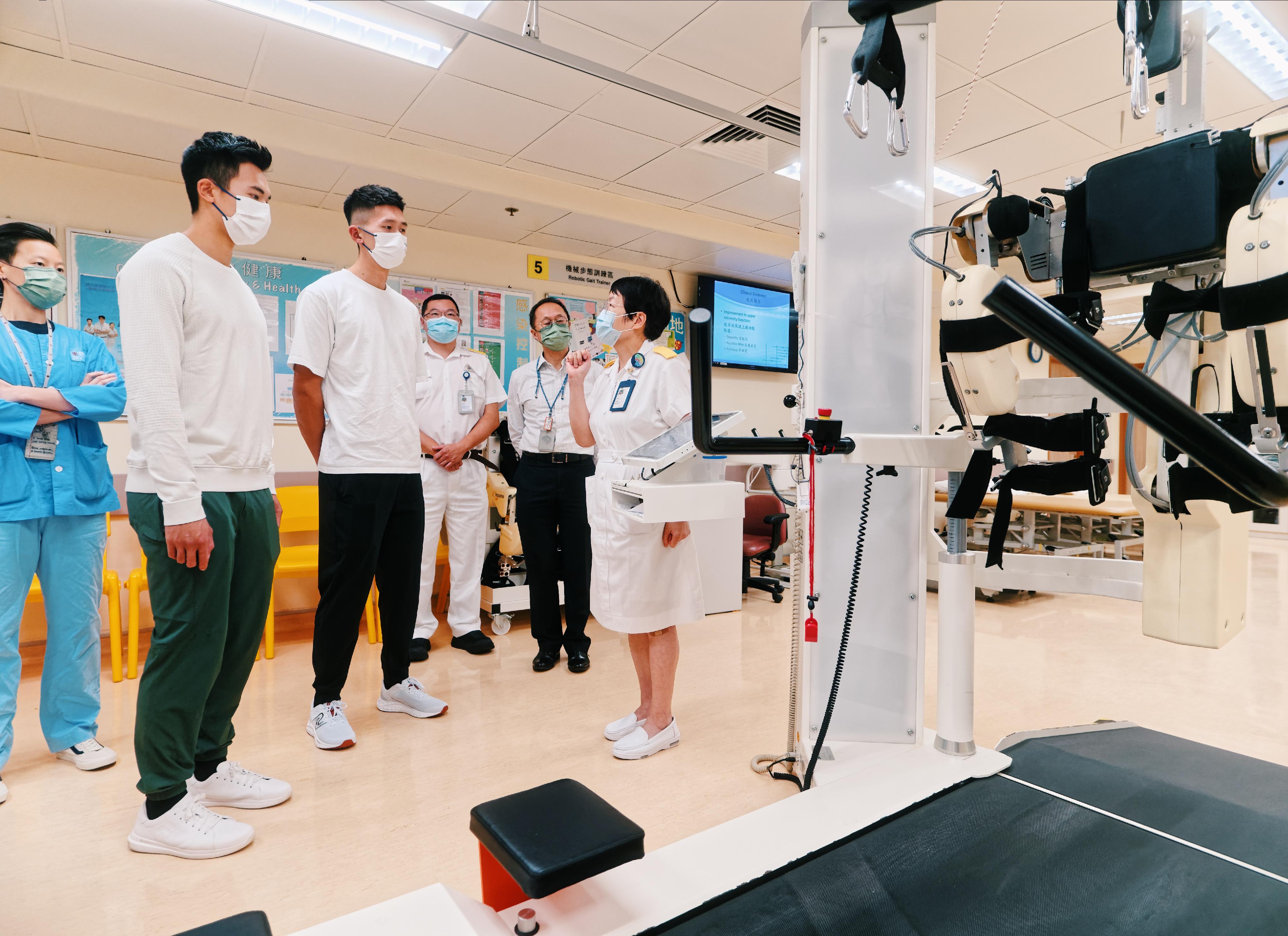 Lam San-tung (second left) and Wong Wai-chun (third left), who won the gold medal in Rowing Men's Coxless Pairs in the 19th Asian Games Hangzhou, visited the Integrated Neurological Rehabilitation Centre of Princess Margaret Hospital and viewed the rehabilitation equipment of the Physiotherapy Department on November 13.