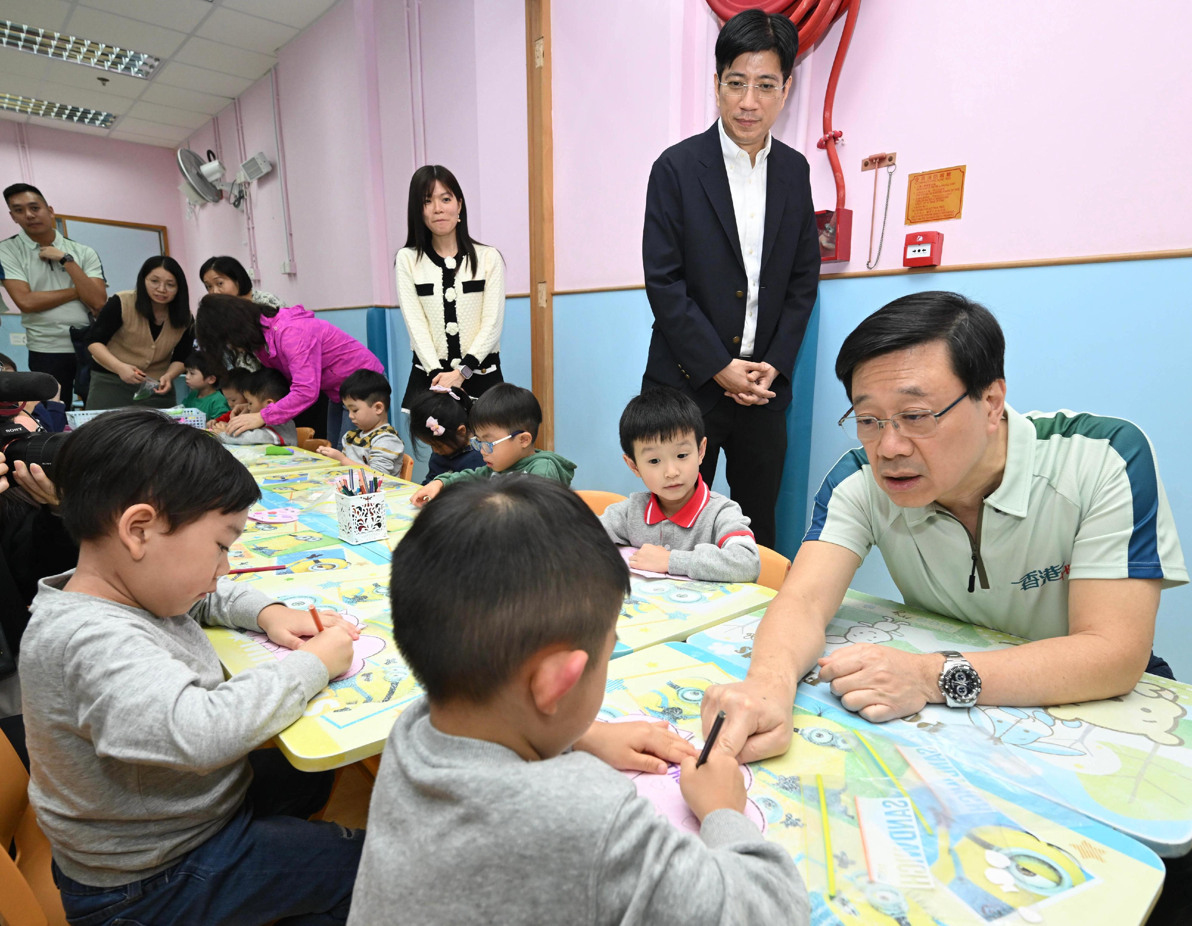 The Chief Executive, Mr John Lee, today (November 15) visited Chinese Evangelical Zion Church Grace After School Care Centre for Pre-primary Children at Tsz Lok Estate, Wong Tai Sin to learn more about its care services provided to parents who are unable to take care of their young children during after-school hours due to work or other reasons. Photo shows Mr Lee (first right) joining children drawing at the centre. 