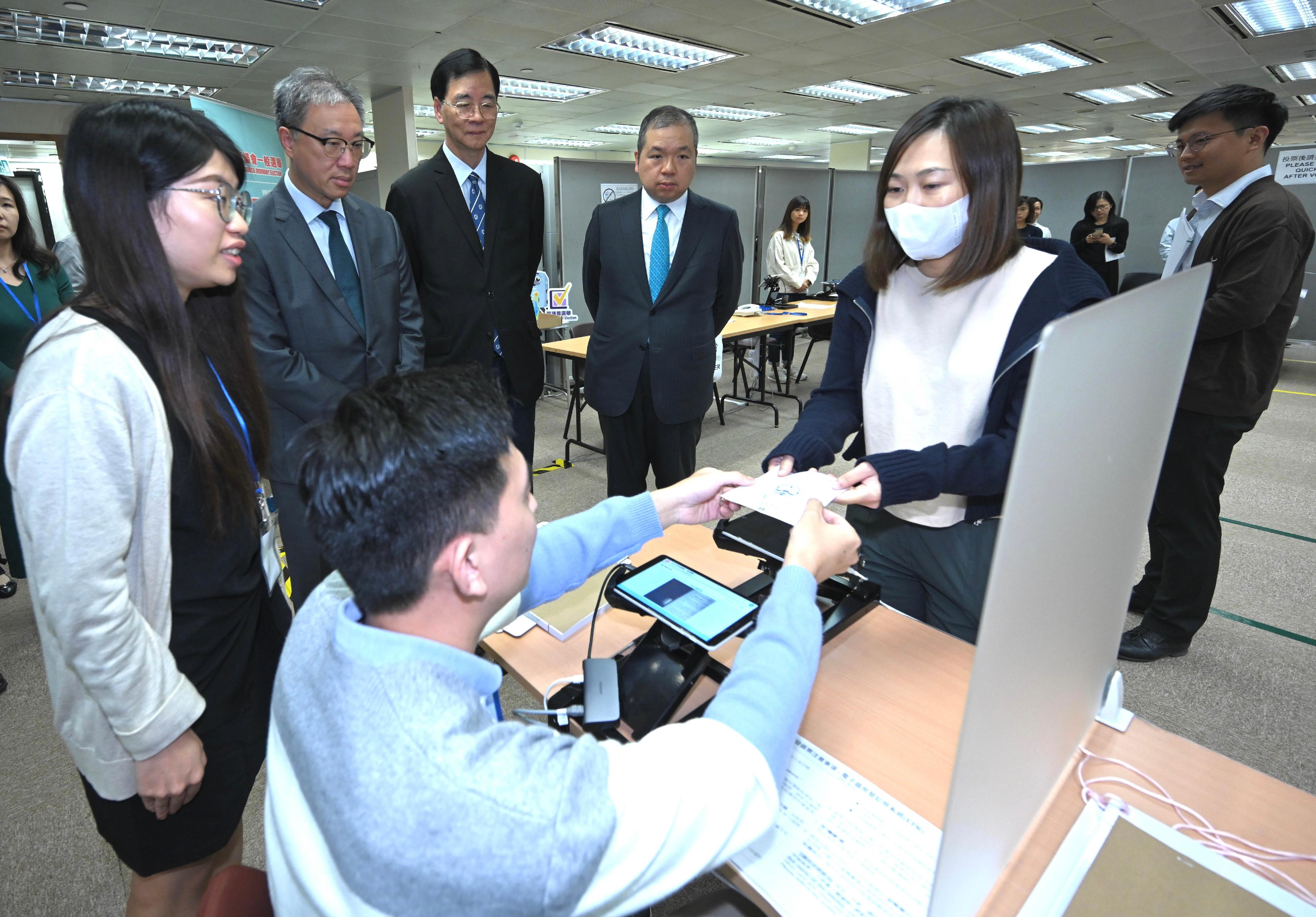 選舉管理委員會（選管會）主席陸啟康法官今日（十一月二十三日）視察選舉事務處的二○二三年區議會一般選舉的投票及點票安排示範。圖示陸啟康法官（左二）、選管會委員石丹理教授（左三）和文本立資深大律師（左四）聽取選舉事務處工作人員示範使用電子選民登記冊系統發出選票的程序。