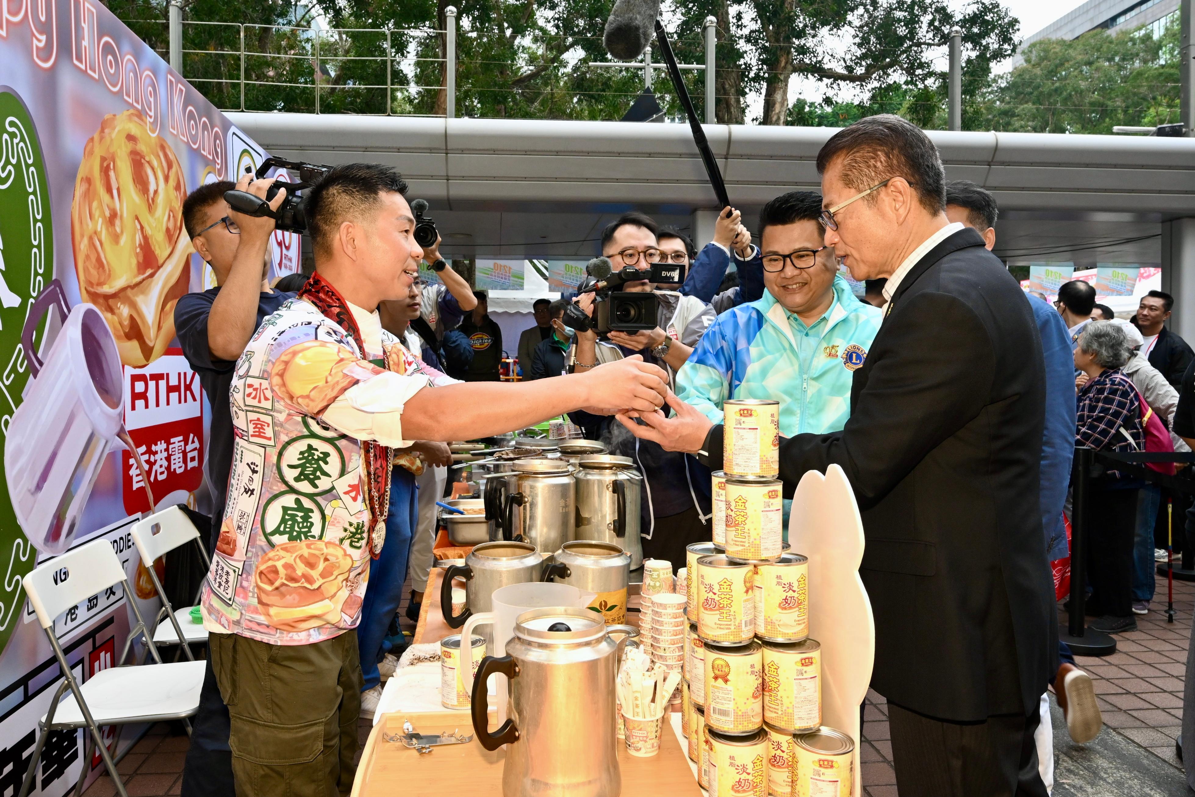 财政司司长陈茂波今日（十二月二日）出席开心香港：声影穿梭——香港公共广播九十五年嘉年华会和展览会活动开幕礼。图示陈茂波（右一）在摊位品尝奶茶。