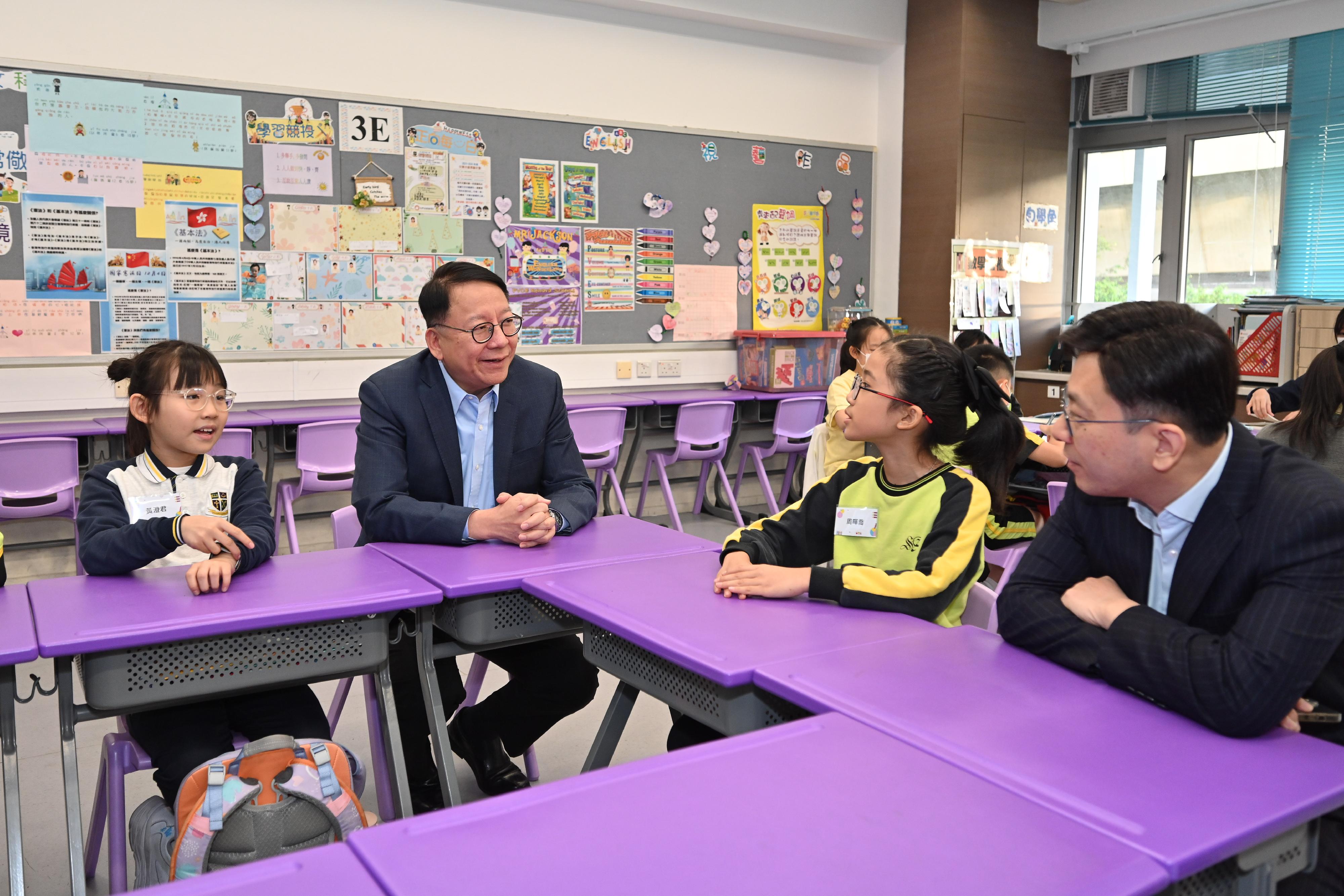 The Chief Secretary for Administration, Mr Chan Kwok-ki, today (December 7) visited SKH St Andrew's Primary School in Sham Shui Po to learn more about the implementation of the School-based After School Care Service Scheme. The Secretary for Labour and Welfare, Mr Chris Sun, and the Acting Secretary for Education, Mr Sze Chun-fai, also joined the visit. Photo shows Mr Chan (second left) and Mr Sun (first right) listening to students sharing how they do homework and revisions in the classroom at school.