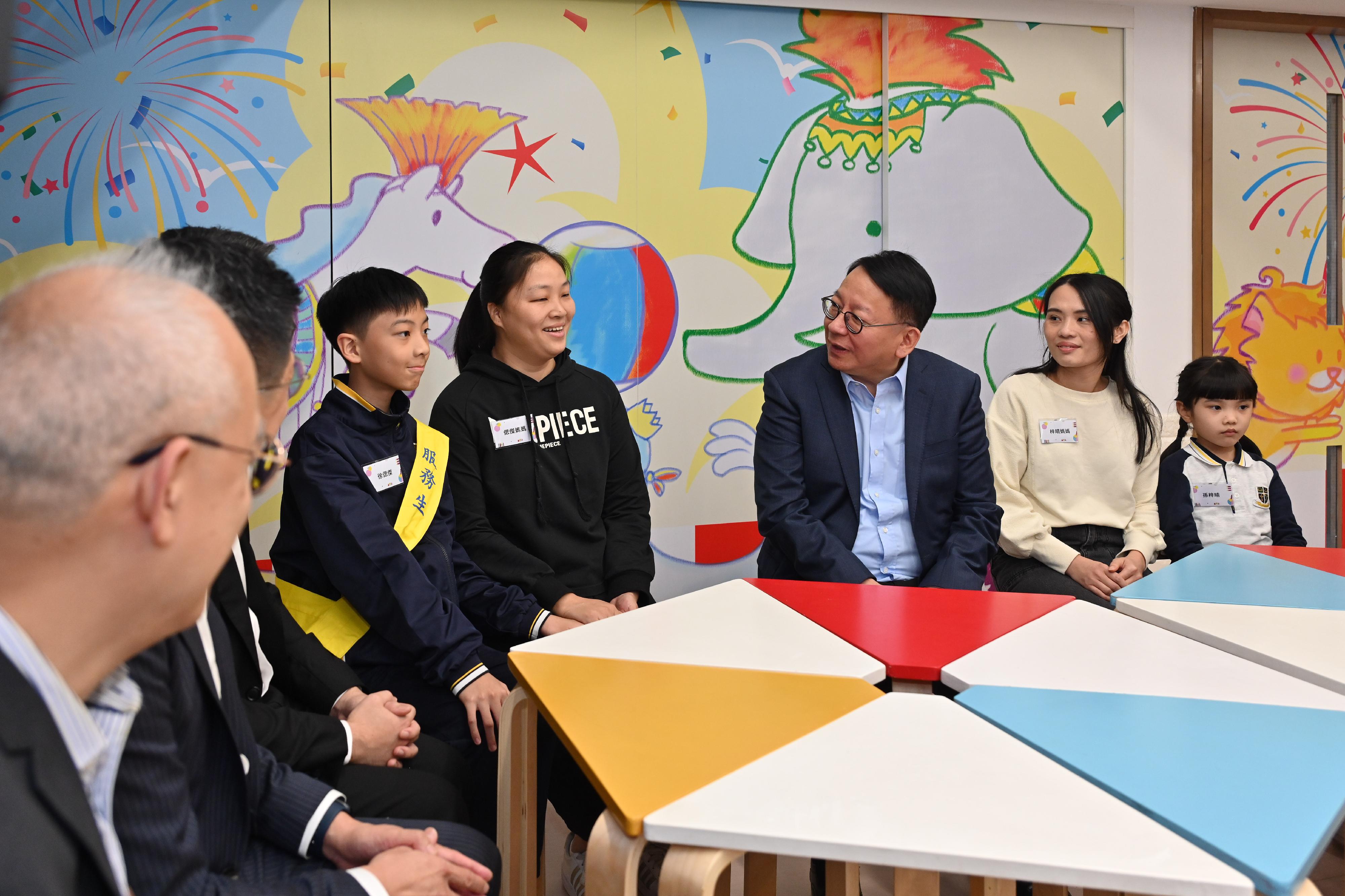 The Chief Secretary for Administration, Mr Chan Kwok-ki, today (December 7) visited SKH St Andrew's Primary School in Sham Shui Po to learn more about the implementation of the School-based After School Care Service Scheme. The Secretary for Labour and Welfare, Mr Chris Sun, and the Acting Secretary for Education, Mr Sze Chun-fai, also joined the visit. Photo shows Mr Chan (third right) chatting with students and parents, noting that they had rejoined the labour market.