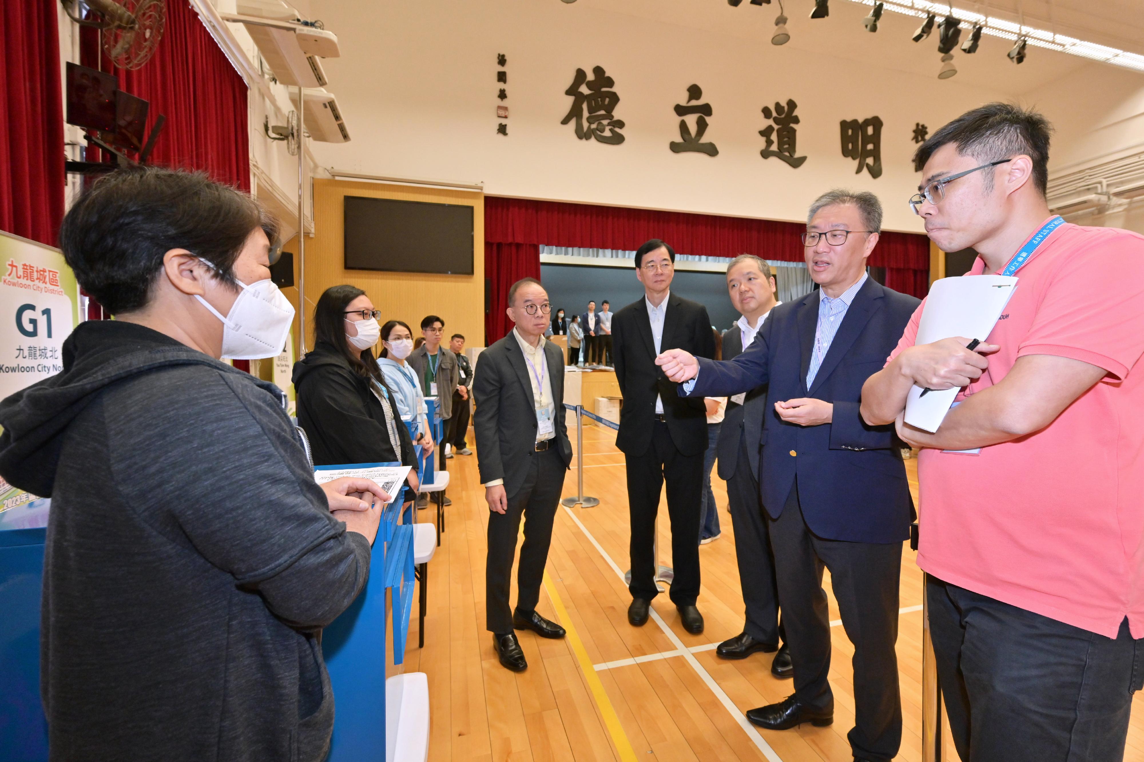 The Chairman of the Electoral Affairs Commission (EAC), Mr Justice David Lok (second right); the Secretary for Constitutional and Mainland Affairs, Mr Erick Tsang Kwok-wai (fifth right); the EAC members Professor Daniel Shek (fourth right) and Mr Bernard Man, SC (third right), visit a near boundary polling station of the 2023 District Council Ordinary Election this afternoon (December 9) to inspect the preparatory work. They are briefed by the polling staff.