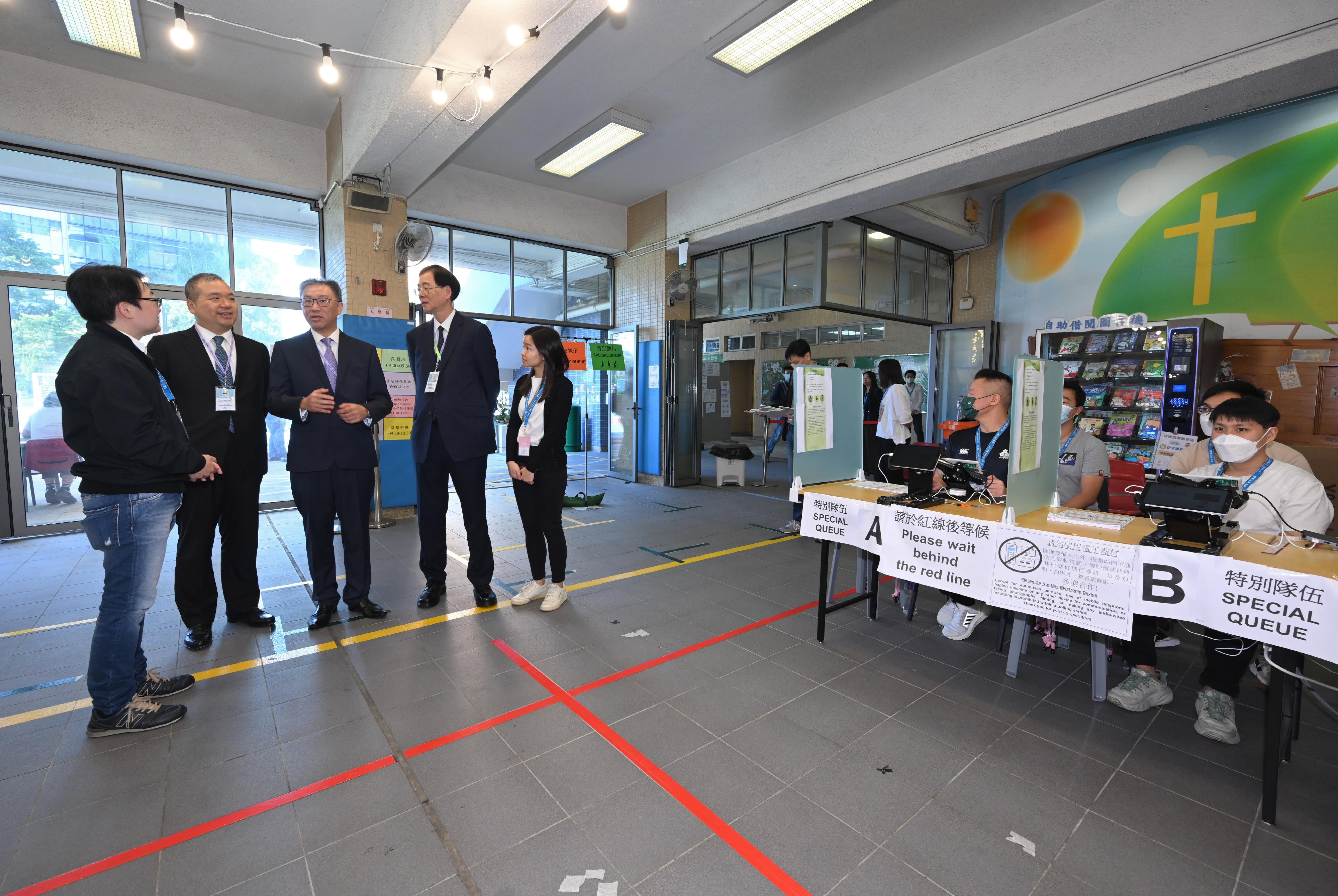 The Chairman of the Electoral Affairs Commission (EAC), Mr Justice David Lok (third left), EAC members Professor Daniel Shek (fourth left) and Mr Bernard Man, SC (second left), visit the District Council geographical constituency polling station of the 2023 District Council Ordinary Election at the Yaumati Catholic Primary School (Hoi Wang Road) this morning (December 10) to inspect the operation of the polling station. They are being briefed by the Presiding Officer.