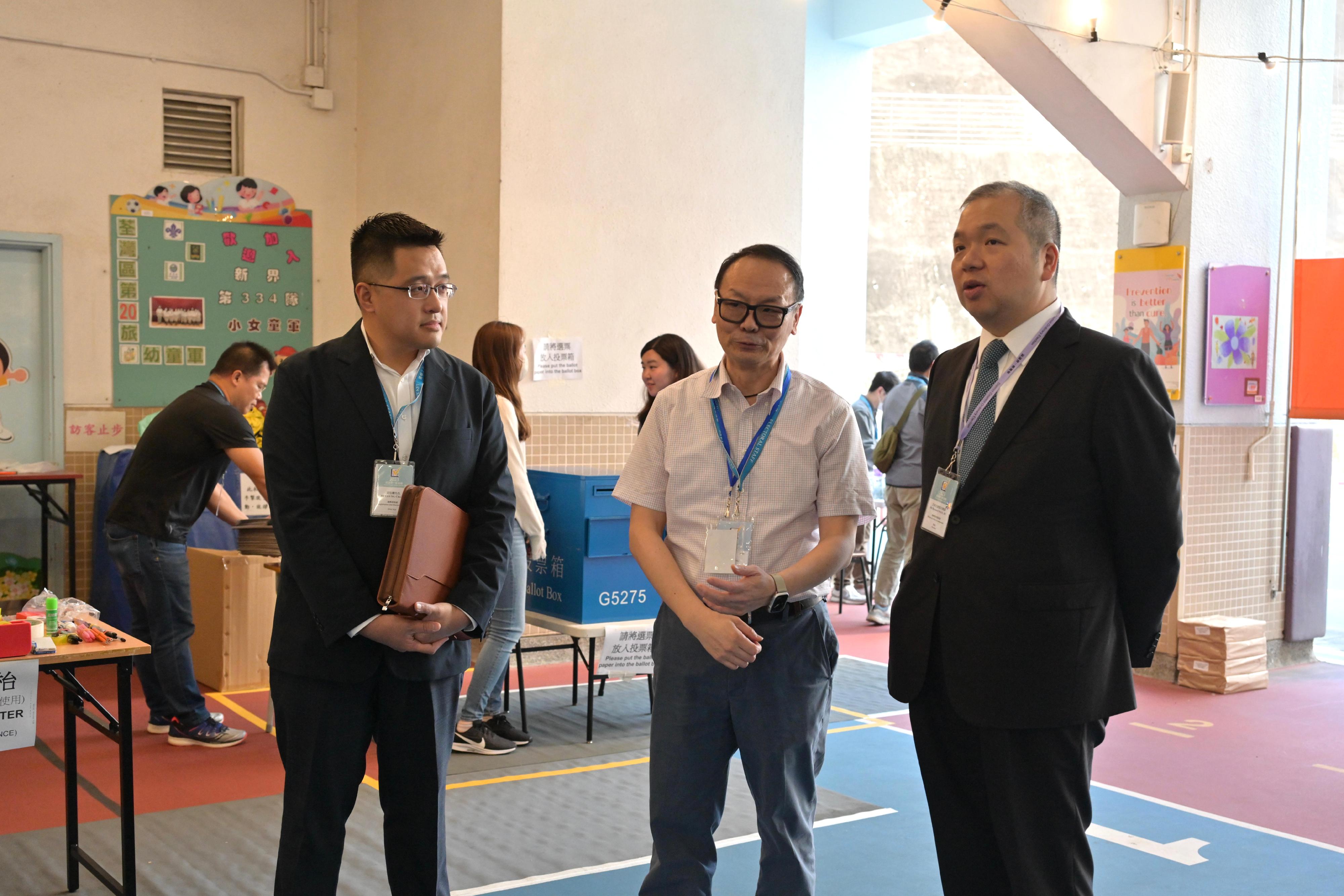 The Electoral Affairs Commission member Mr Bernard Man, SC (first right) visits the District Council geographical constituency polling station of the 2023 District Council Ordinary Election at the Tsuen Wan Government Primary School this afternoon (December 10) to inspect the operation of the polling station. He is being briefed by the Presiding Officer.
