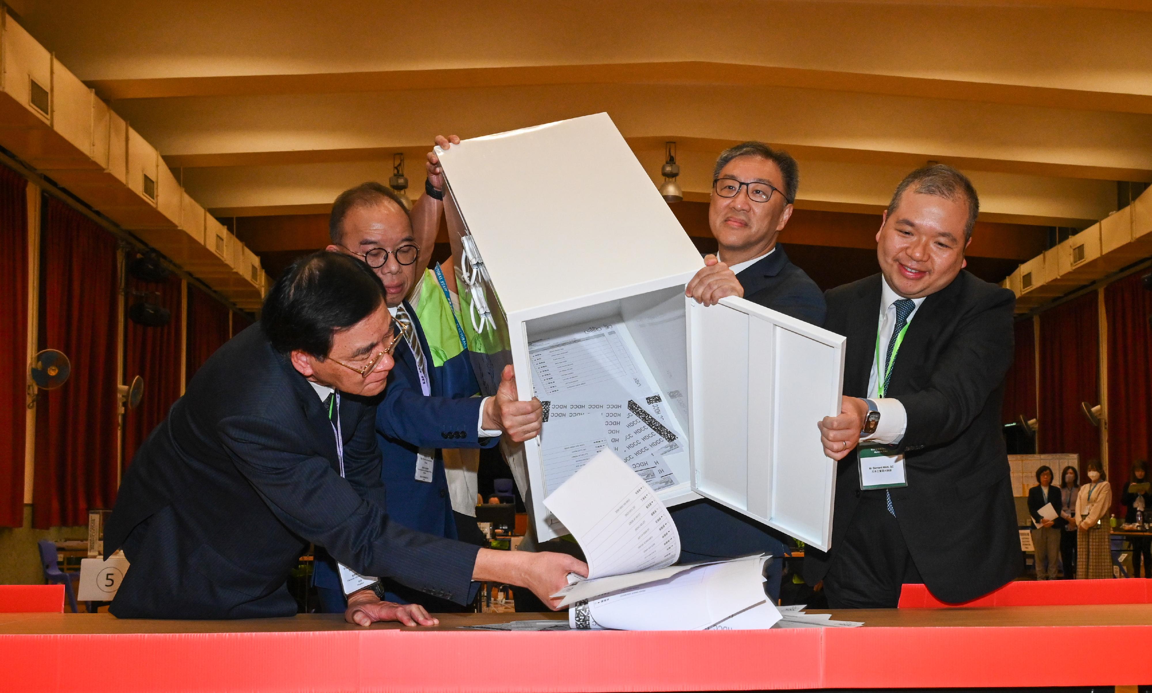 The Chairman of the Electoral Affairs Commission (EAC), Mr Justice David Lok (second right), and the Secretary for Constitutional and Mainland Affairs, Mr Erick Tsang Kwok-wai (second left), empty a ballot box at the District Committees constituency counting station of the 2023 District Council Ordinary Election at Ng Wah Catholic Secondary School last night (December 10). Also present are the EAC members Professor Daniel Shek (first left) and Mr Bernard Man, SC (first right).