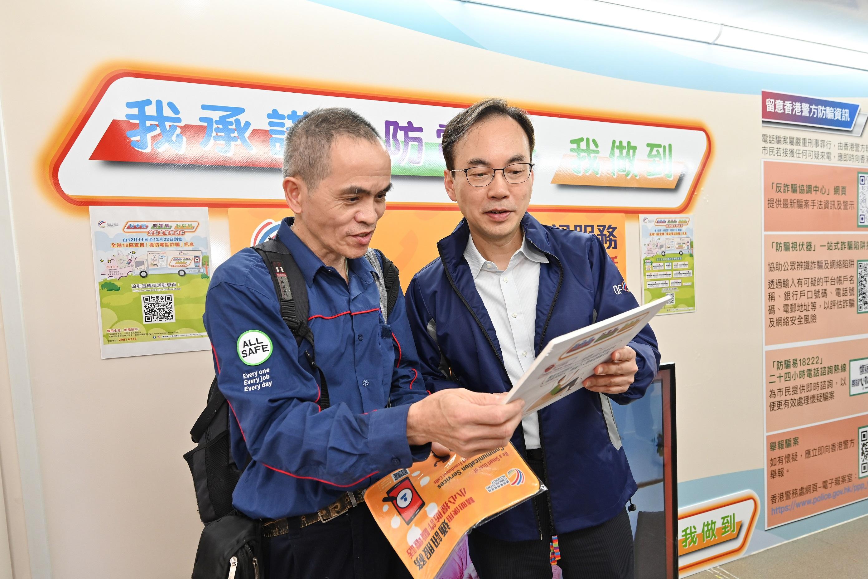 The Communications Authority today (December 11) launched a promotion truck tour campaign themed "My Promise against Phone Scams" to enhance publicity against telephone scams. Photo shows the Director-General of Communications, Mr Chaucer Leung (right), visiting the promotion truck and joining a visitor at the tongue twister game.