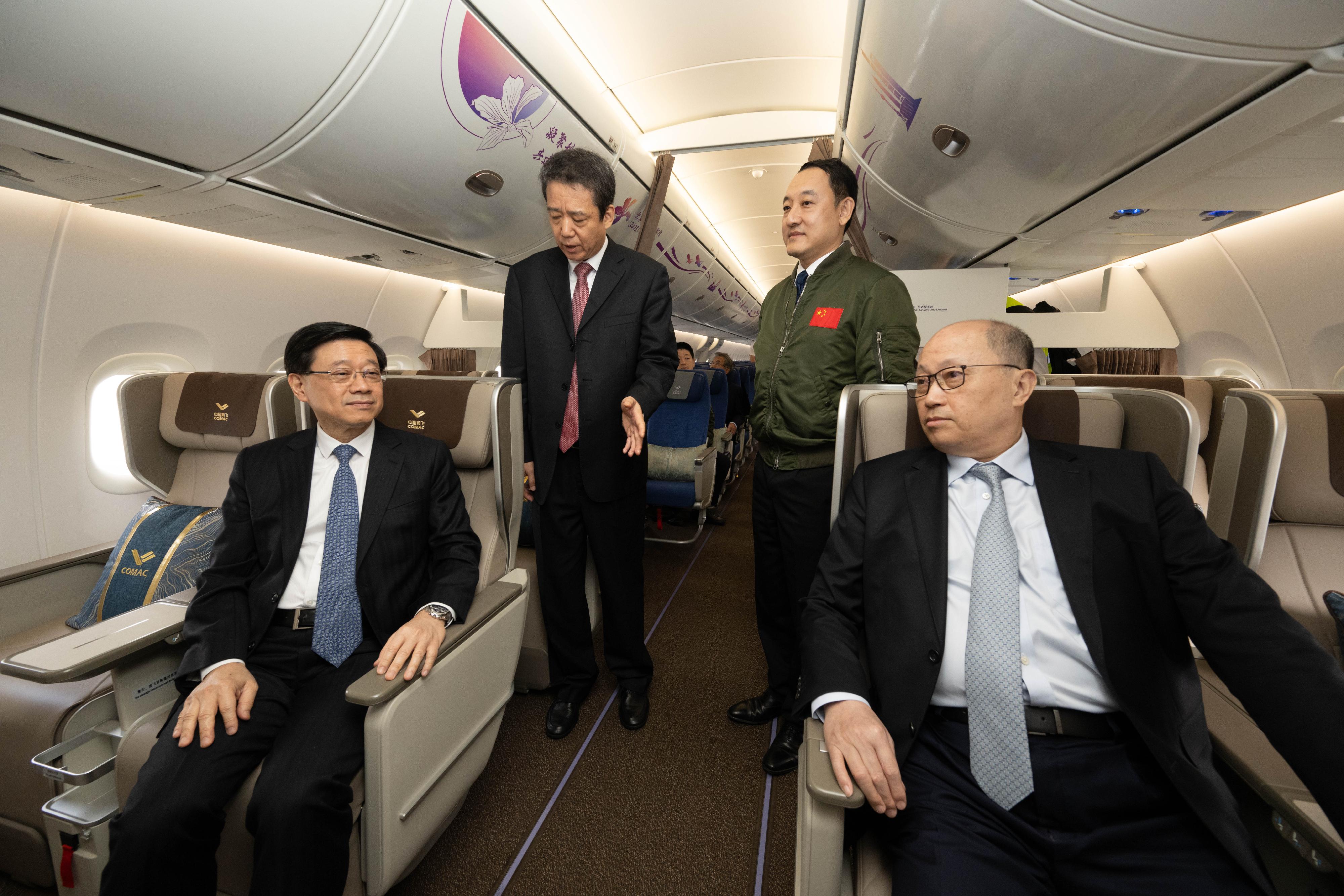 The Chief Executive, Mr John Lee, attended the welcome ceremony for aircraft C919 and ARJ21 today (December 13). Photo shows Mr Lee (front row, left) and the Director of the Liaison Office of the Central People's Government in the Hong Kong Special Administrative Region, Mr Zheng Yanxiong (front row, right), being briefed by Deputy Administrator of the Civil Aviation Administration of China Mr Cui Xiaofeng (back row, left), in the business class cabin of aircraft C919.
