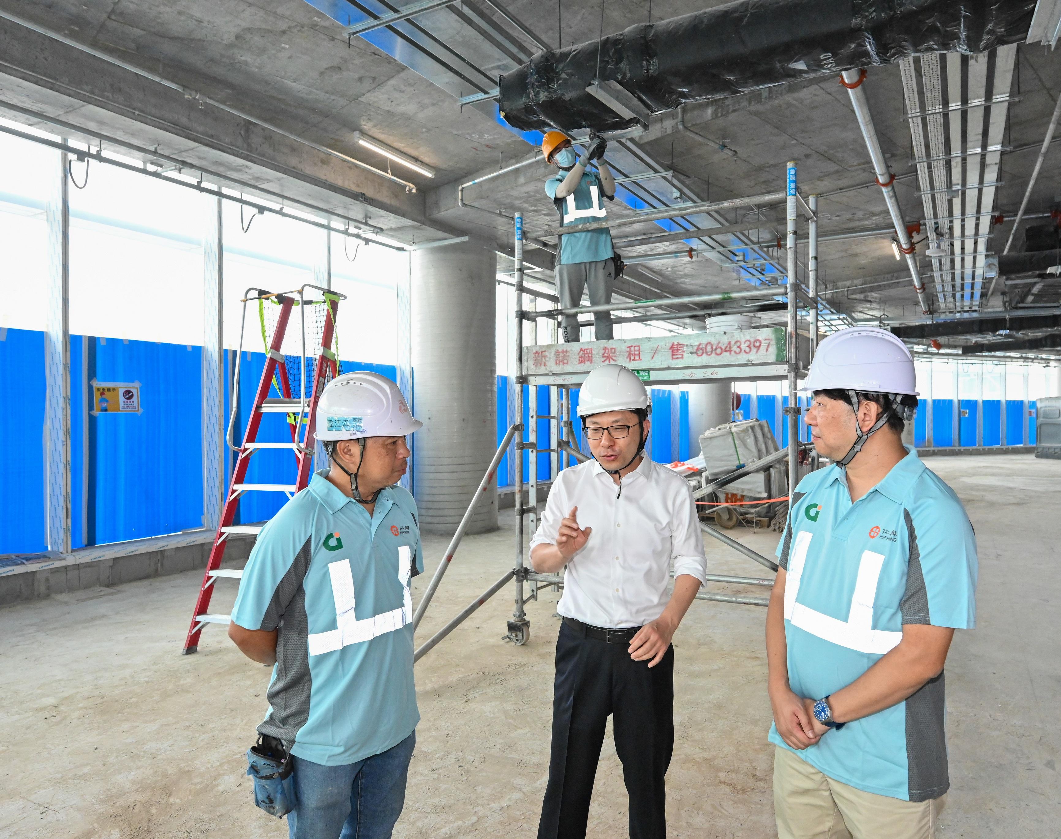 The Secretary for Labour and Welfare, Mr Chris Sun (centre), visits a construction site today (December 13) to call on workers to pay attention to work safety. 