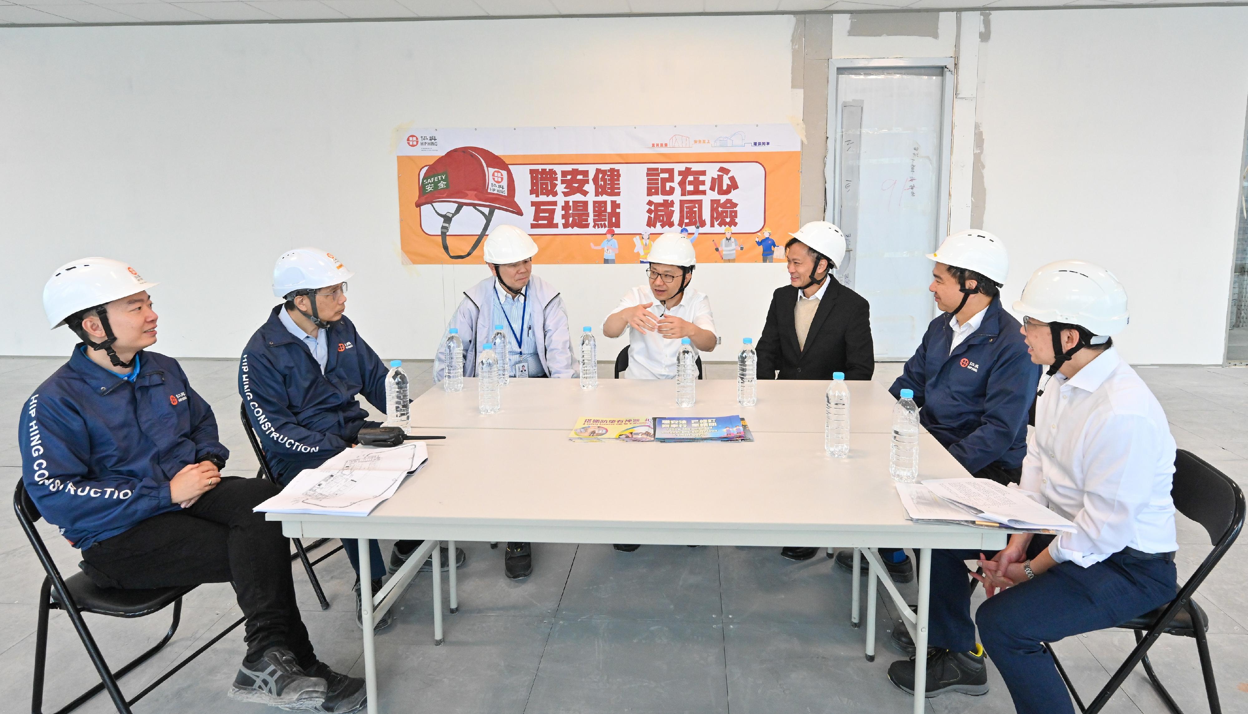 The Secretary for Labour and Welfare, Mr Chris Sun, visited a construction site today (December 13) to call on contractors, employers and workers to pay attention to work safety. Photo shows Mr Sun (centre), the Deputy Commissioner for Labour (Occupational Safety and Health), Mr Vincent Fung (third left), and an officer of the Labour Department exchanging views with the project manager of the construction site, management staff of the contractor and a representative of the property owner on promoting occupational safety.