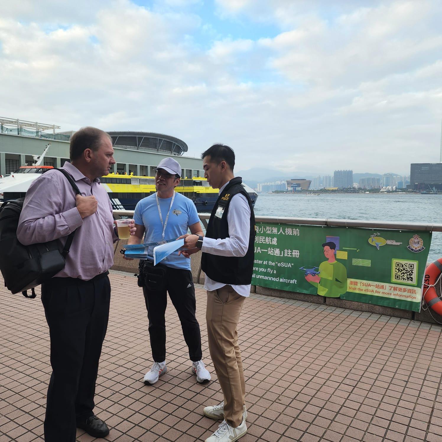 The Civil Aviation Department (CAD) conducted a joint publicity operation with the Police today (December 13) to enhance the safety awareness of the public and tourists of small unmanned aircraft operations. Photo shows a member of the public receiving publicity materials from CAD and Police officers along Victoria Harbour and being reminded about the establishment of a temporary restricted flying zone along Victoria Harbour this Saturday (December 16).