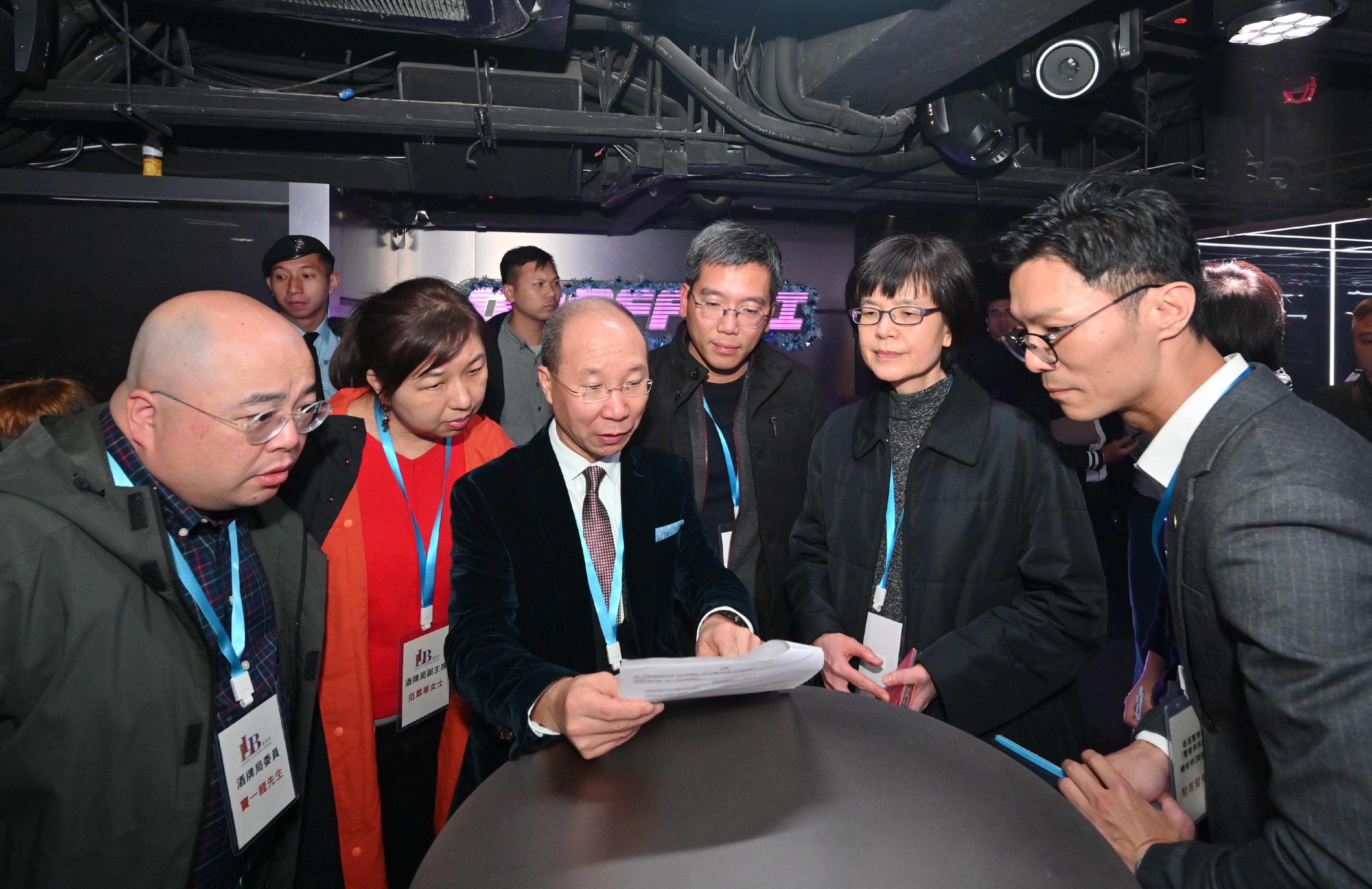 Members of the Liquor Licensing Board, led by the Board Chairman, Dr Wong Kong-tin, visited a number of premises with liquor licences in Central District and Tsim Sha Tsui District in the small hours today (December 17) to learn more about the operation of the premises and enforcement action by the Police and the Fire Services Department. Photo shows Dr Wong (third left); the Permanent Secretary for Environment and Ecology (Food), Miss Vivian Lau (second right); and the Acting Director of Food and Environmental Hygiene, Mr Arsene Yiu (third right), viewing the liquor licence of a premises.
