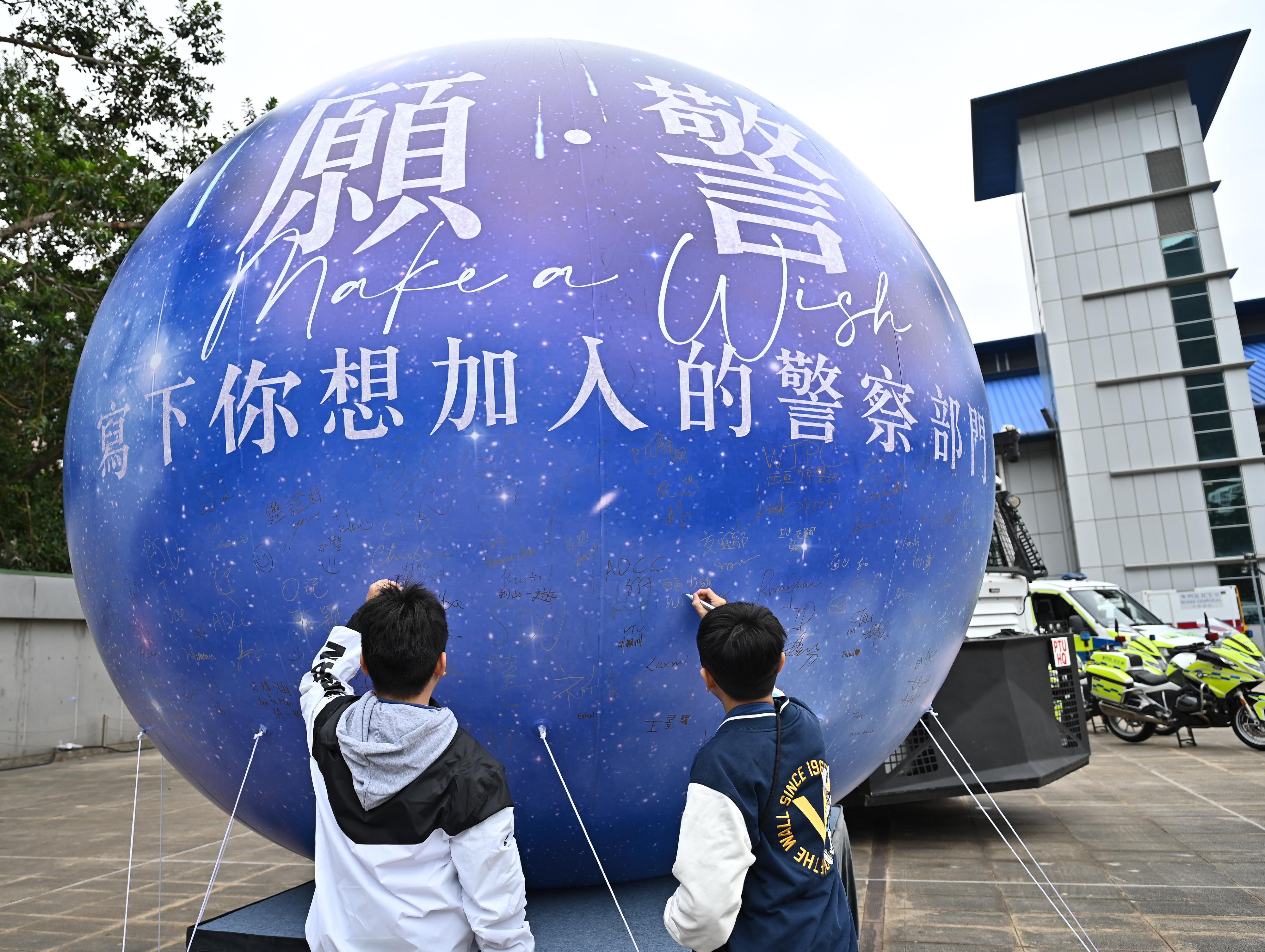 警队今日（十二月十七日）在香港警察学院举办「警察招募．体验日」，以「愿•警」为主题。图示参加者于会场的巨型许愿气球写下希望加入的警队部门。