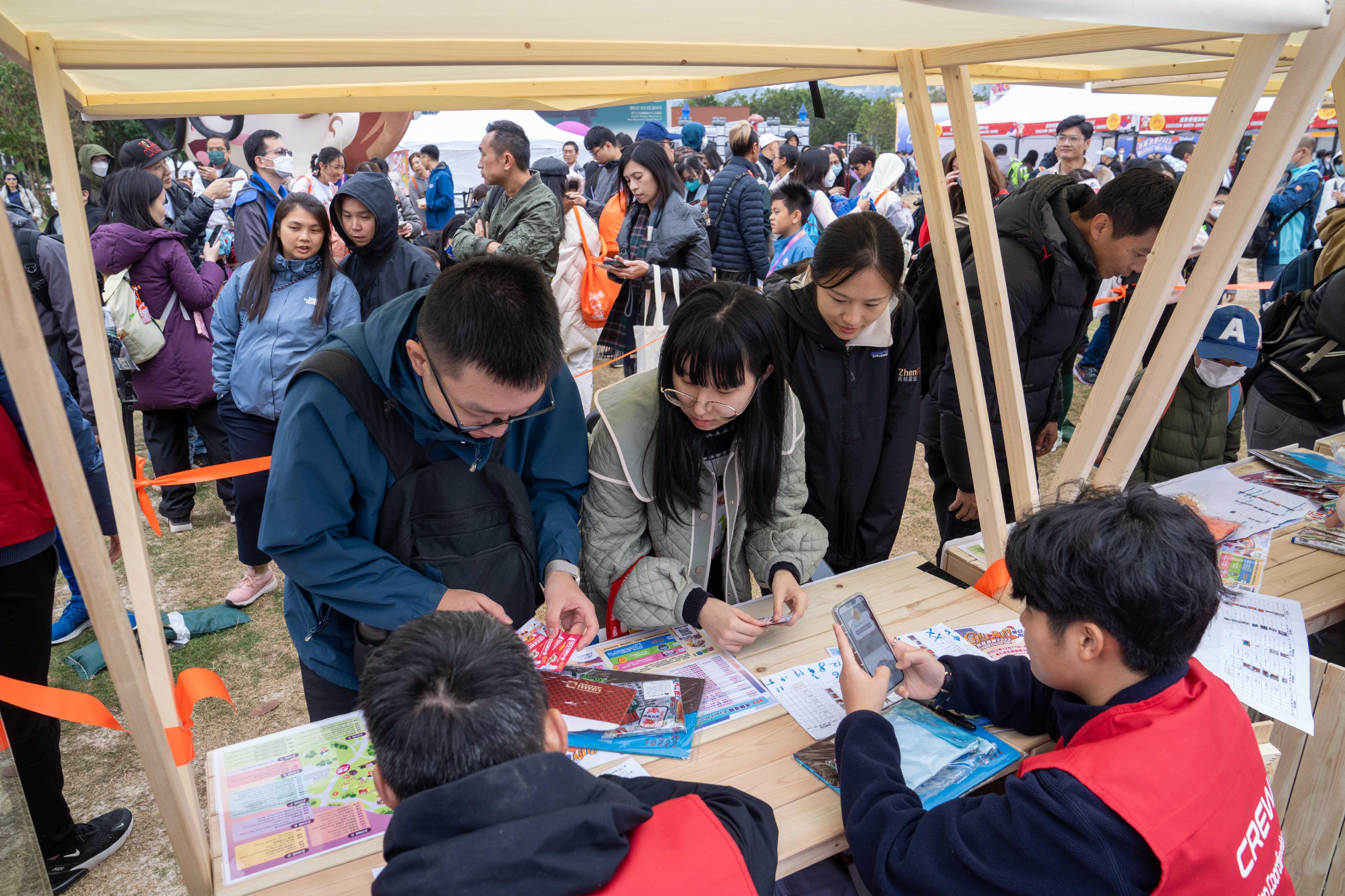 The Anti-Deception Coordination Centre of the Hong Kong Police Force organises the "West Kowloon CHILL RUN Winter Market cum Anti-Scam Charity Run 2023" at the West Kowloon Cultural District today (December 17). Photo shows the event booths promoting scam prevention messages, which attracted a large number of members of the public to visit.