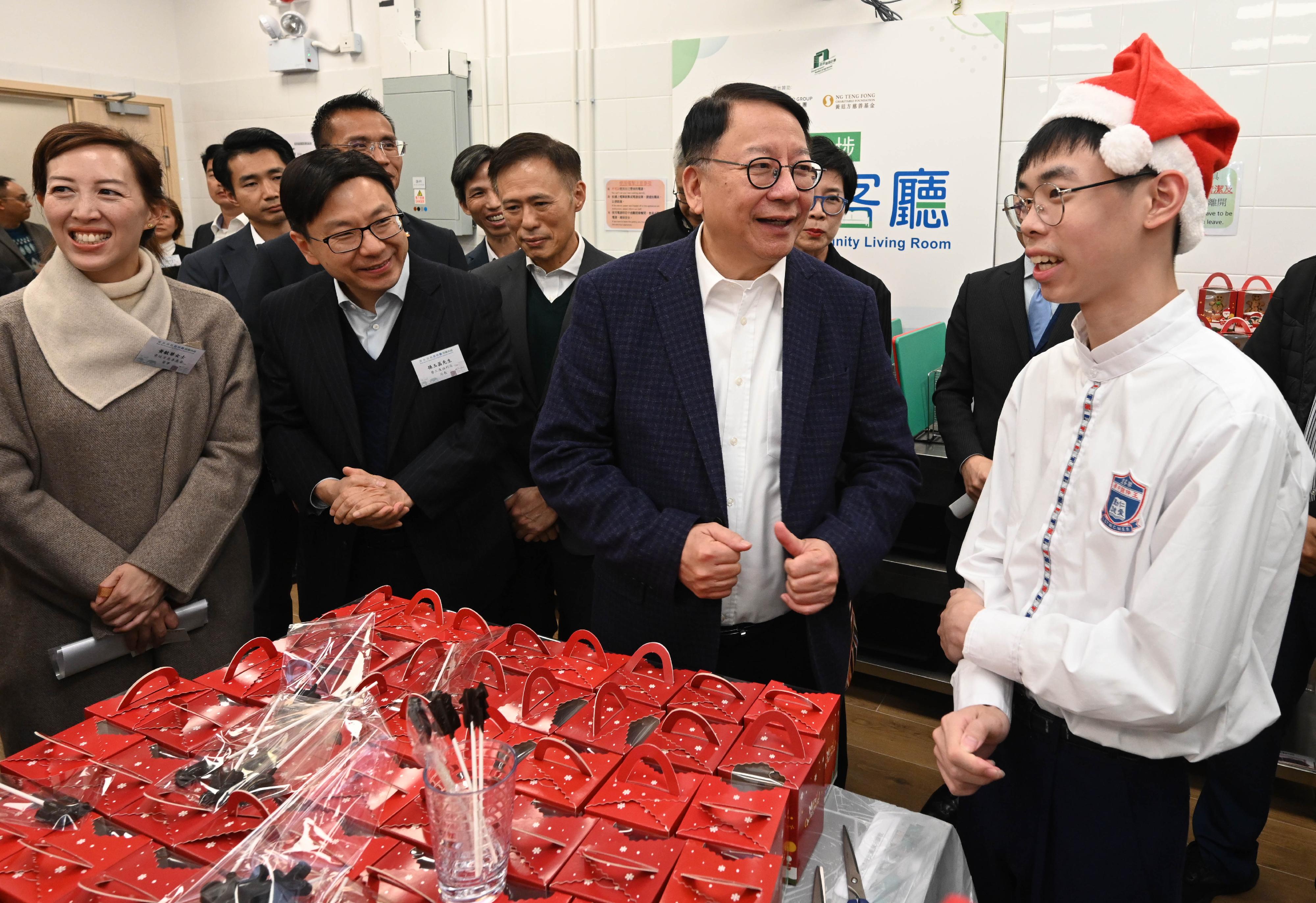 The Chief Secretary for Administration and Chairperson of the Commission on Poverty, Mr Chan Kwok-ki, today (December 18) visited the Sham Shui Po Community Living Room, the first project under the Pilot Programme on Community Living Room. The Secretary for Labour and Welfare, Mr Chris Sun, also joined the visit. Photo shows Mr Chan (front row, second right) and Mr Sun (front row, third right) watching sub-divided unit households preparing Christmas foods in the shared pantry.