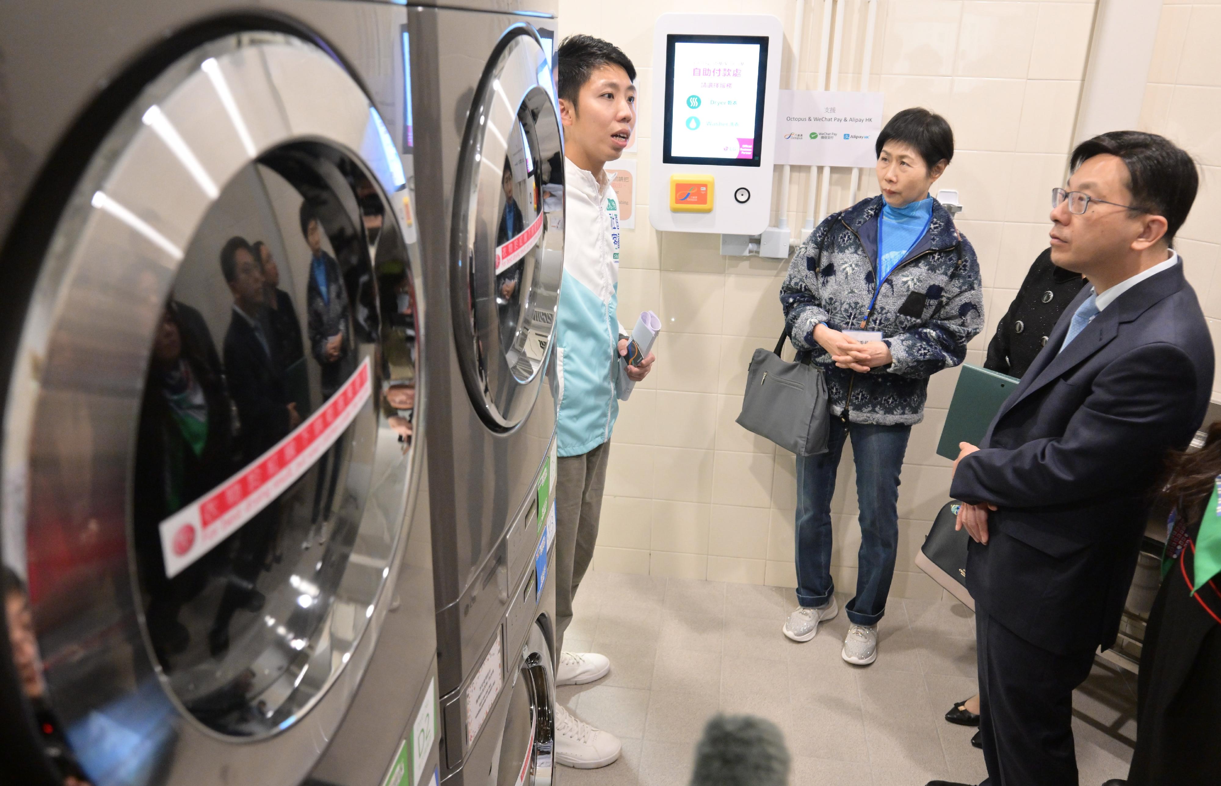 The fifth-term Commission on Poverty today (January 4) visited the first project under the Pilot Programme on Community Living Room, the Sham Shui Po Community Living Room. The Secretary for Labour and Welfare, Mr Chris Sun, also joined the visit. Photo shows Mr Sun (right) and members looking at the self-service laundry, which provides convenience to sub-divided unit households.