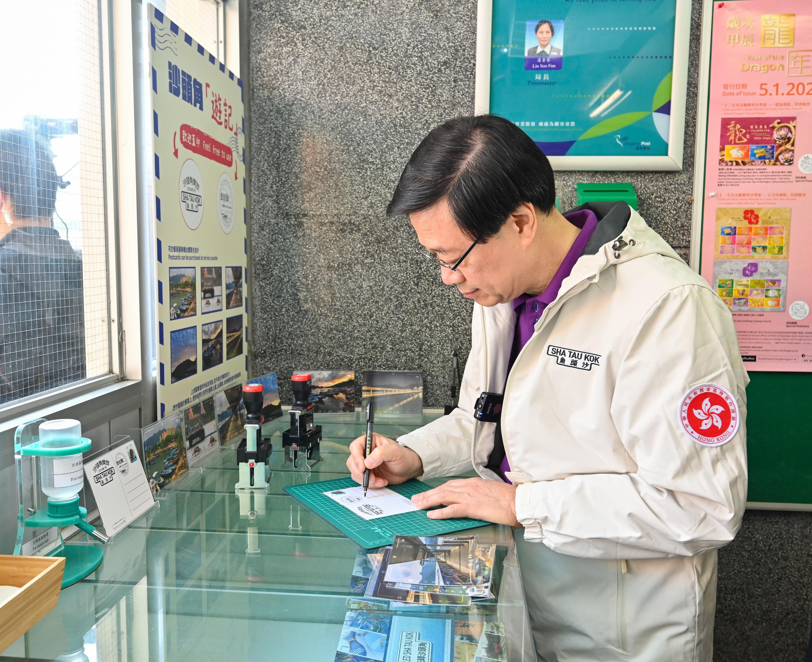 The Chief Executive, Mr John Lee, officiated at the Second Phase Opening-up of Sha Tau Kok Launching Ceremony today (January 6). Photo shows Mr Lee writing on a postcard at the Sha Tau Kok Post Office.