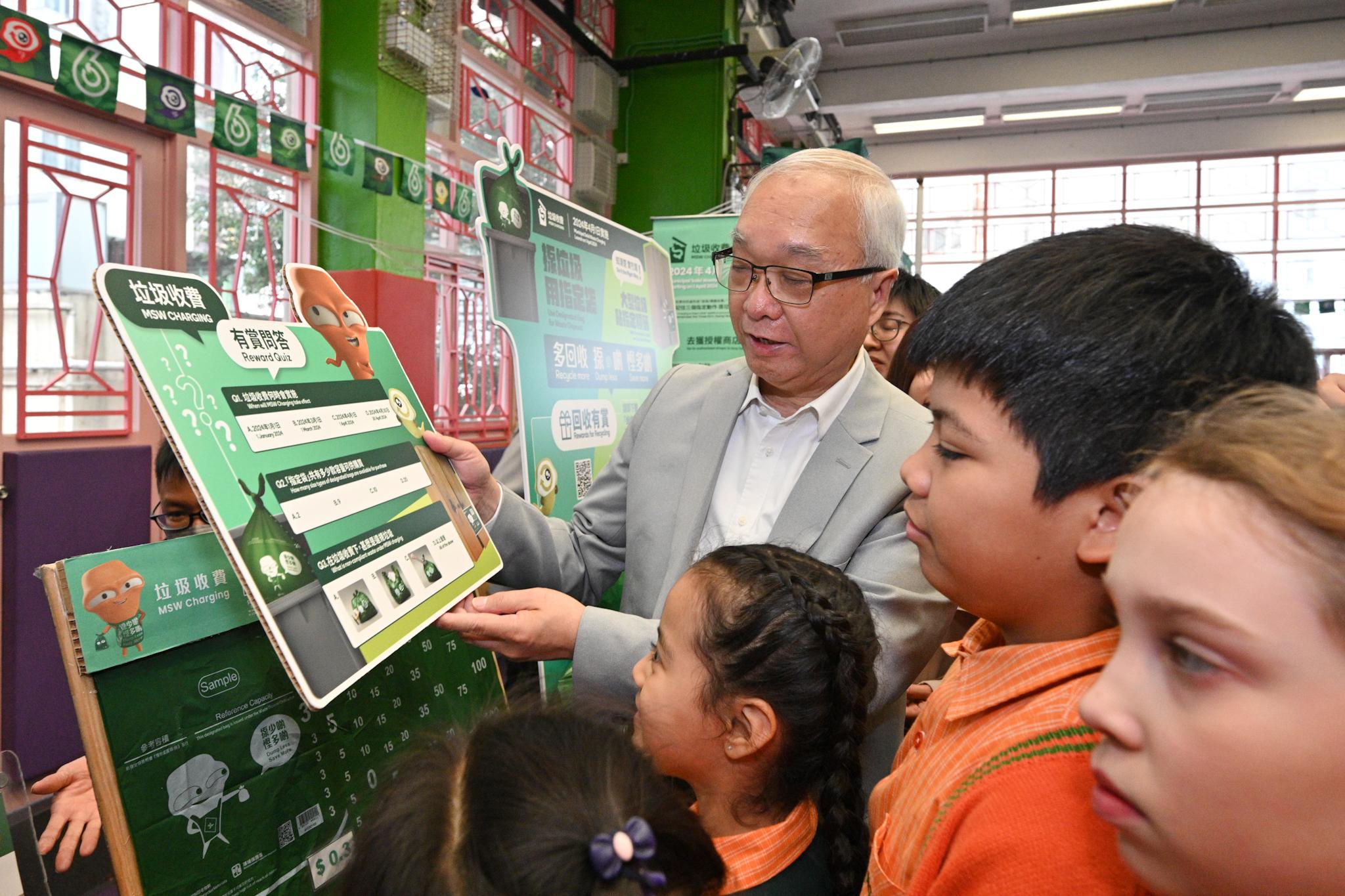 The Secretary for Environment and Ecology, Mr Tse Chin-wan, and the Under Secretary for Education, Mr Sze Chun-fai, today (January 16) visited the Yaumati Kaifong Association School to promote municipal solid waste charging to students. Photo shows Mr Tse browsing the information board on municipal solid waste charging with school students.