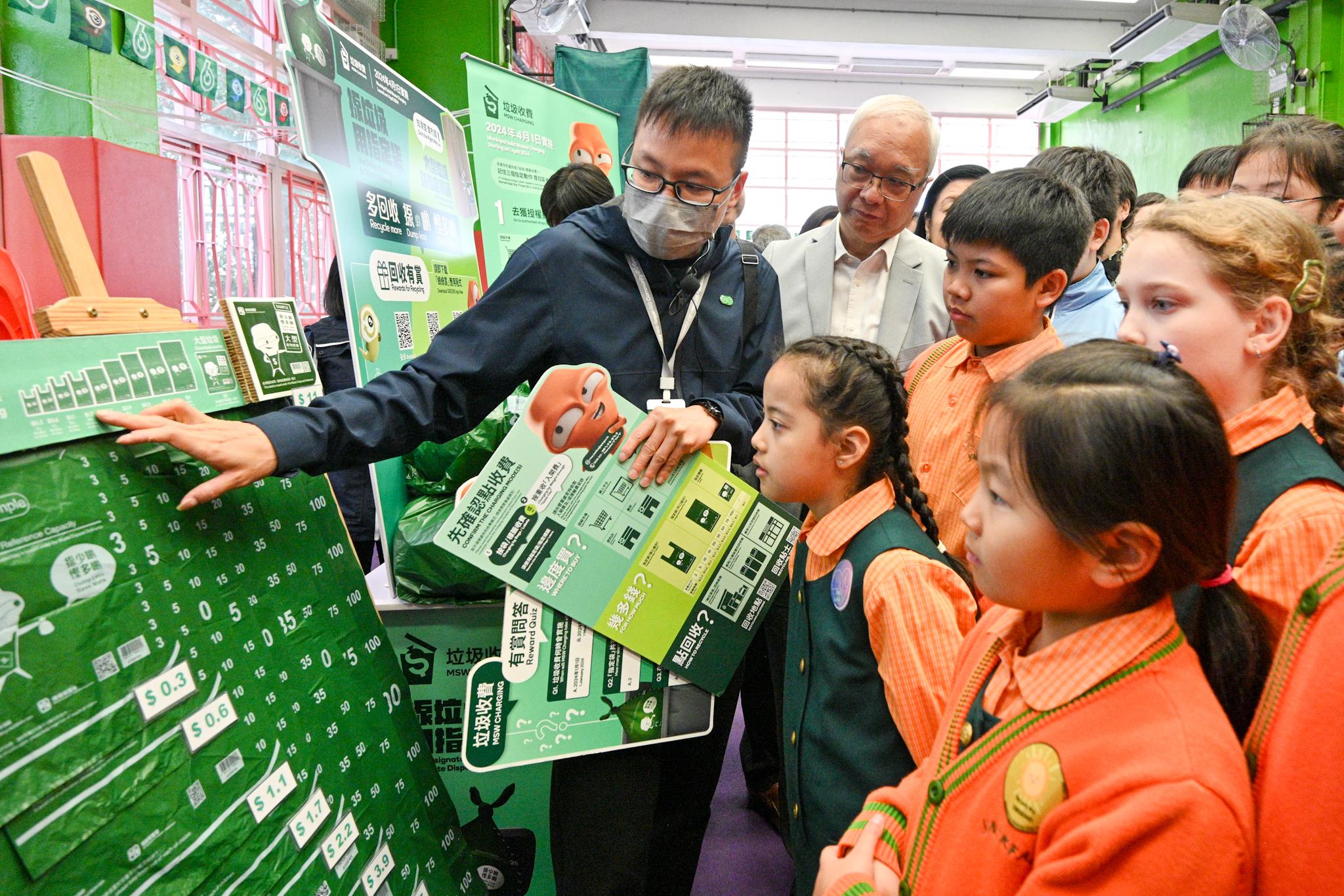 The Secretary for Environment and Ecology, Mr Tse Chin-wan, and the Under Secretary for Education, Mr Sze Chun-fai, today (January 16) visited Yaumati Kaifong Association School to promote municipal solid waste charging to students. Photo shows Mr Tse (second left) browsing the information board on municipal solid waste charging with school students.