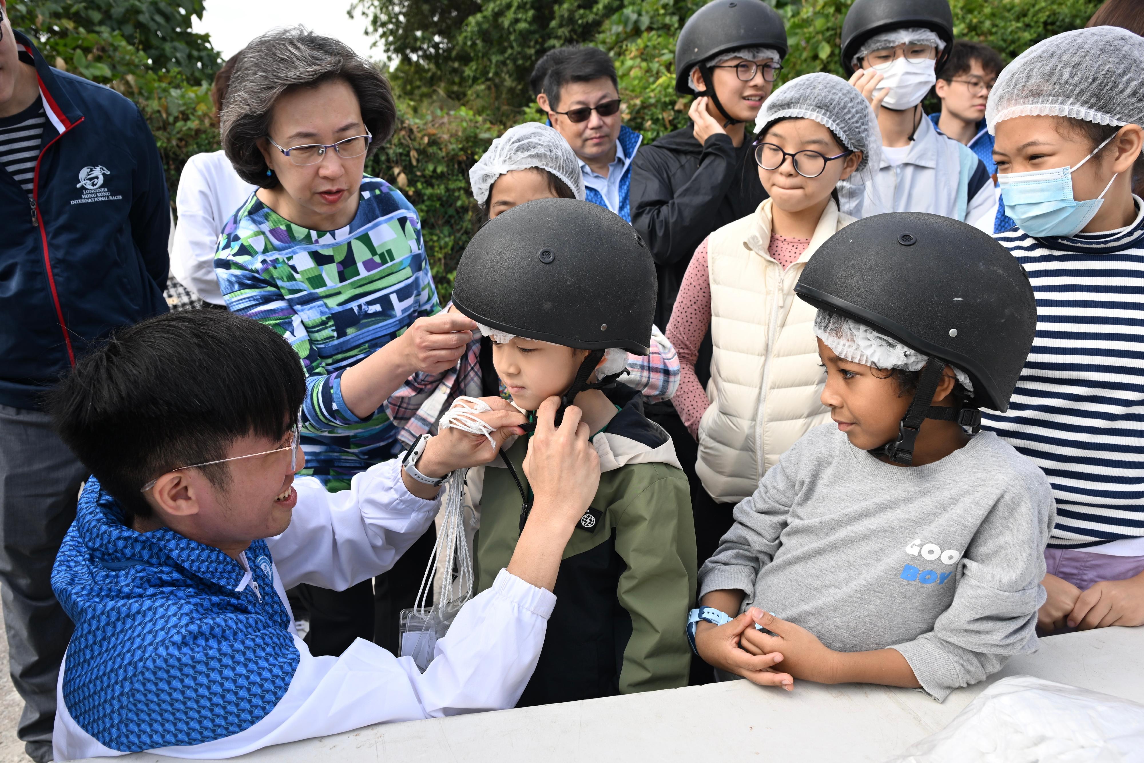 About 20 children from grassroots families today (January 20) visited the Tuen Mun Public Riding School in the company of civil service volunteers to sample the fun of horse riding. Photo shows the Secretary for the Civil Service, Mrs Ingrid Yeung (second left), and volunteers from the Water Supplies Department helping a child get ready before the ride.