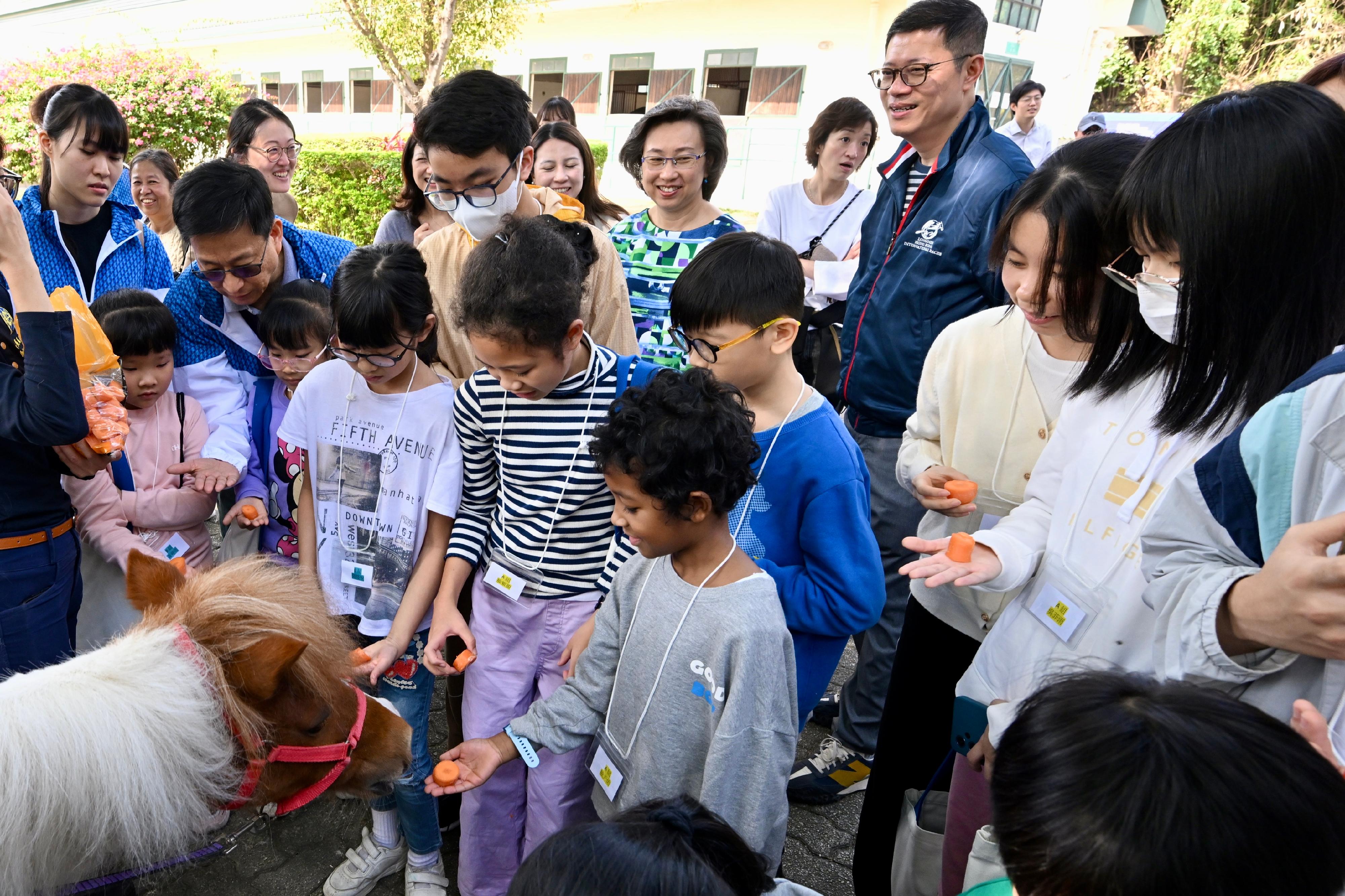 About 20 children from grassroots families today (January 20) visited the Tuen Mun Public Riding School in the company of civil service volunteers to sample the fun of horse riding and learn about the environment of horses at the stables. Photo shows the children having fun in feeding ponies.
