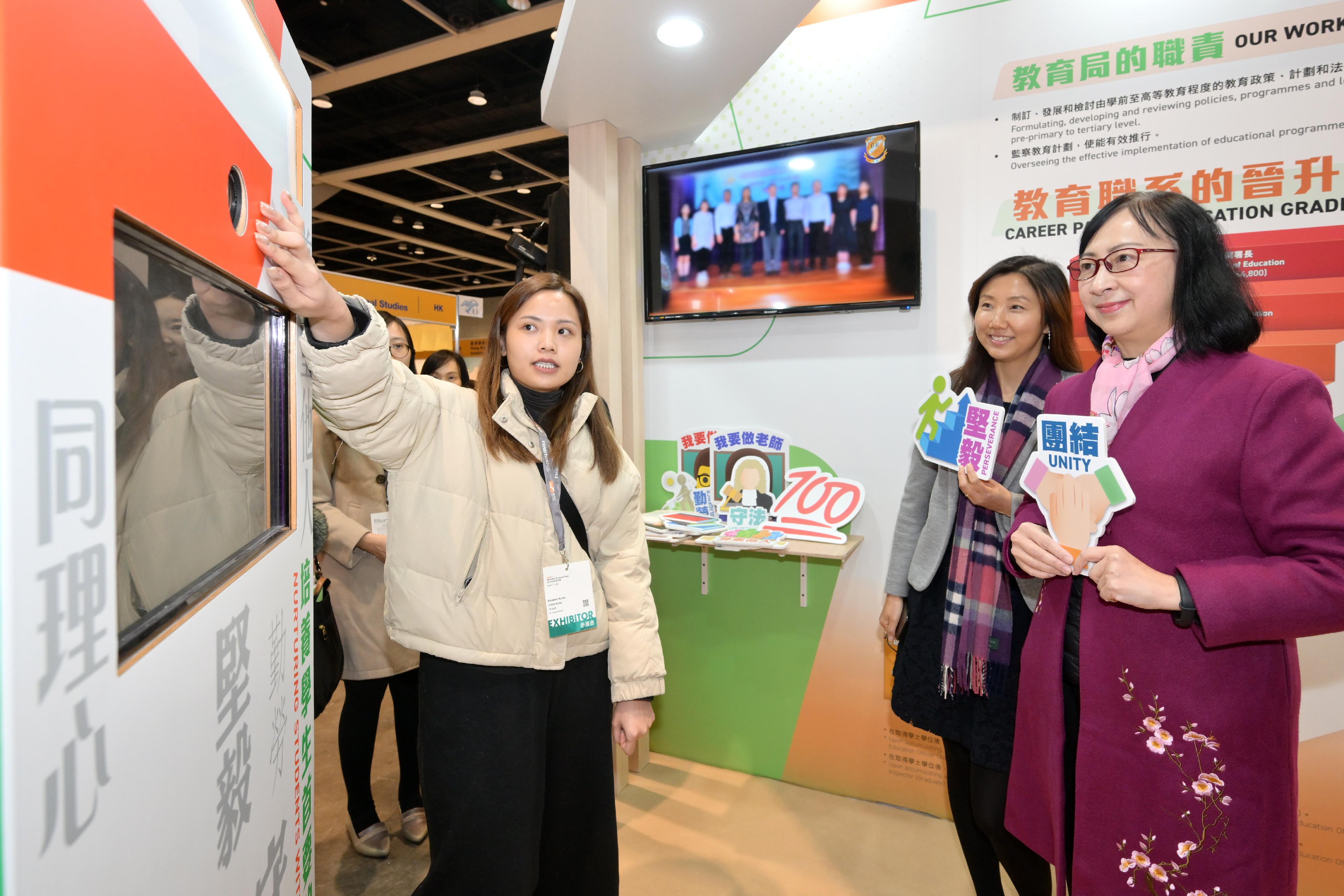 The Permanent Secretary for Education, Ms Michelle Li (first right), visits a booth of the Education Bureau and tries out the photo booth at the Education & Careers Expo 2024 today (January 25).
