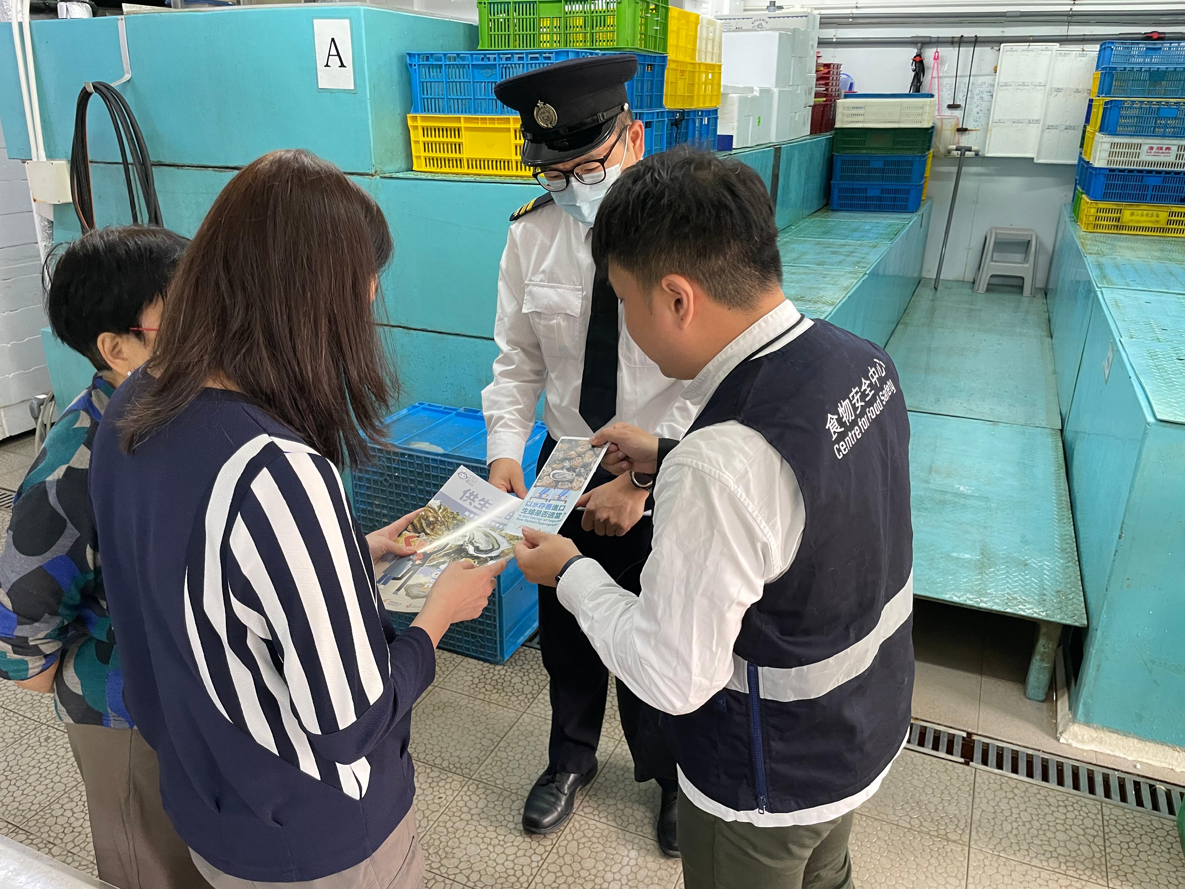 To safeguard food safety and protect public health, the Centre for Food Safety and the Environmental Hygiene Branch of the Food and Environmental Hygiene Department (FEHD) have enhanced inspections before the Lunar New Year holidays to various licensed food premises across the territory to ensure that oysters to be eaten in a raw state (raw oysters) be stored at the proper temperature. Photo shows FEHD officers distributing food safety pamphlets during an operation to staff of food premises regarding the proper way of storing raw oysters.