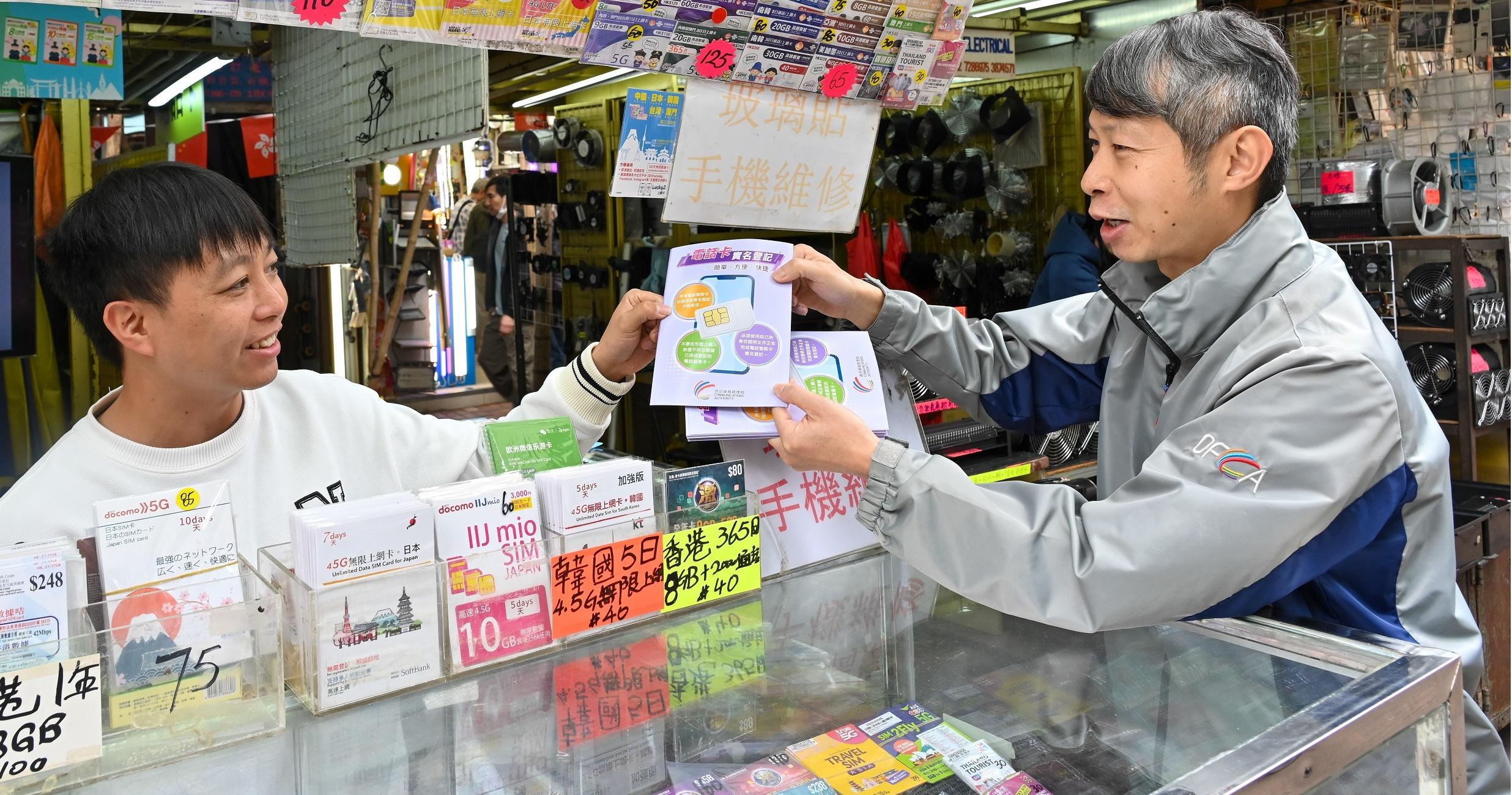 The Office of the Communications Authority (OFCA) conducted today (February 6) market surveillance, publicity and education activities around Apliu Street in Sham Shui Po on real-name registration for SIM cards before the Lunar New Year. Photo shows an OFCA staff member (right) distributing pamphlets to remind a trader not to assist any persons in using the identity document of any third party in completing real-name registration, and not to sell pre-paid SIM cards allegedly having completed registration.