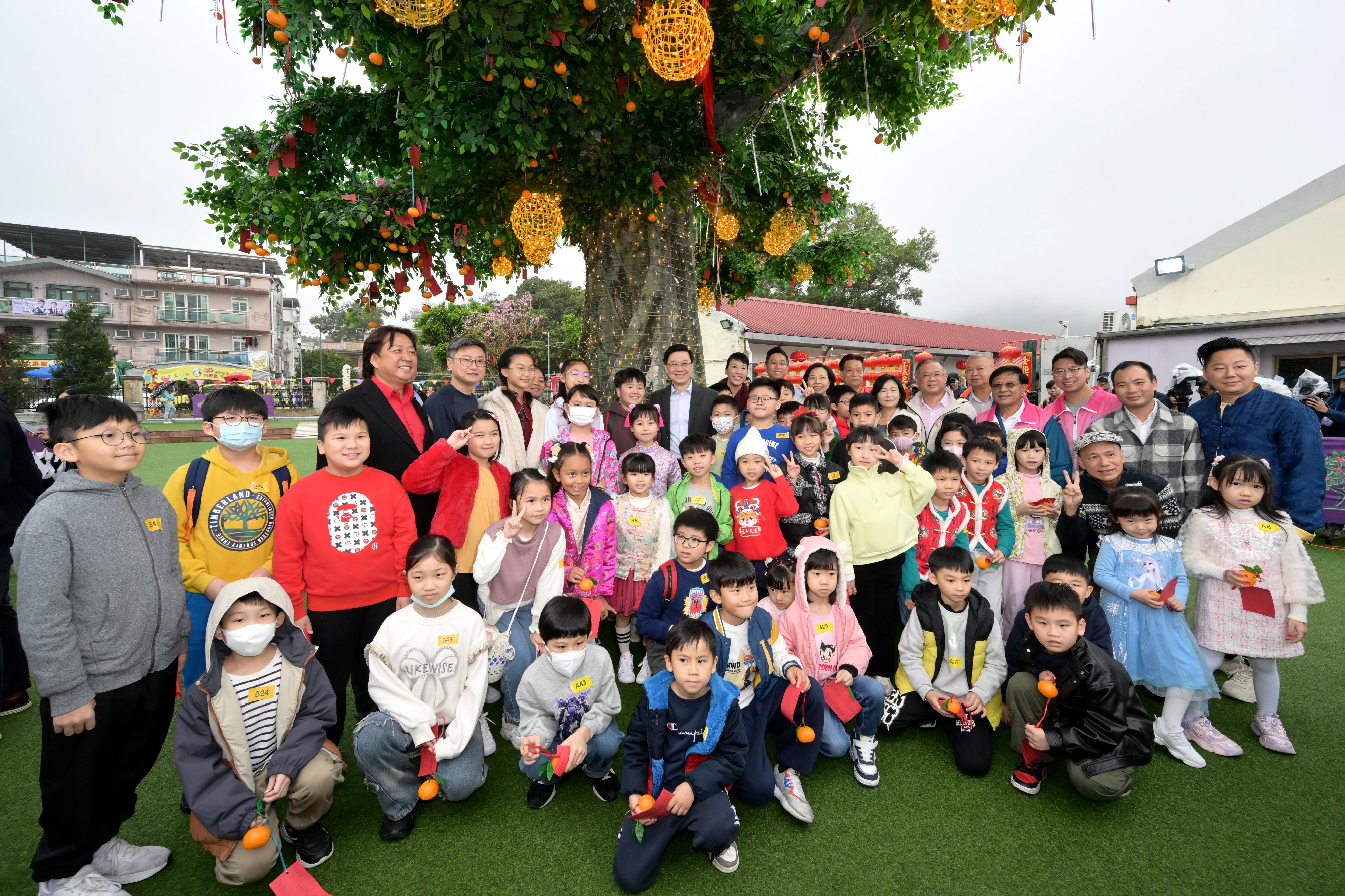 The Chief Executive, Mr John Lee (third row, sixth left), visits Tai Po today (February 7) and is pictured with children.  