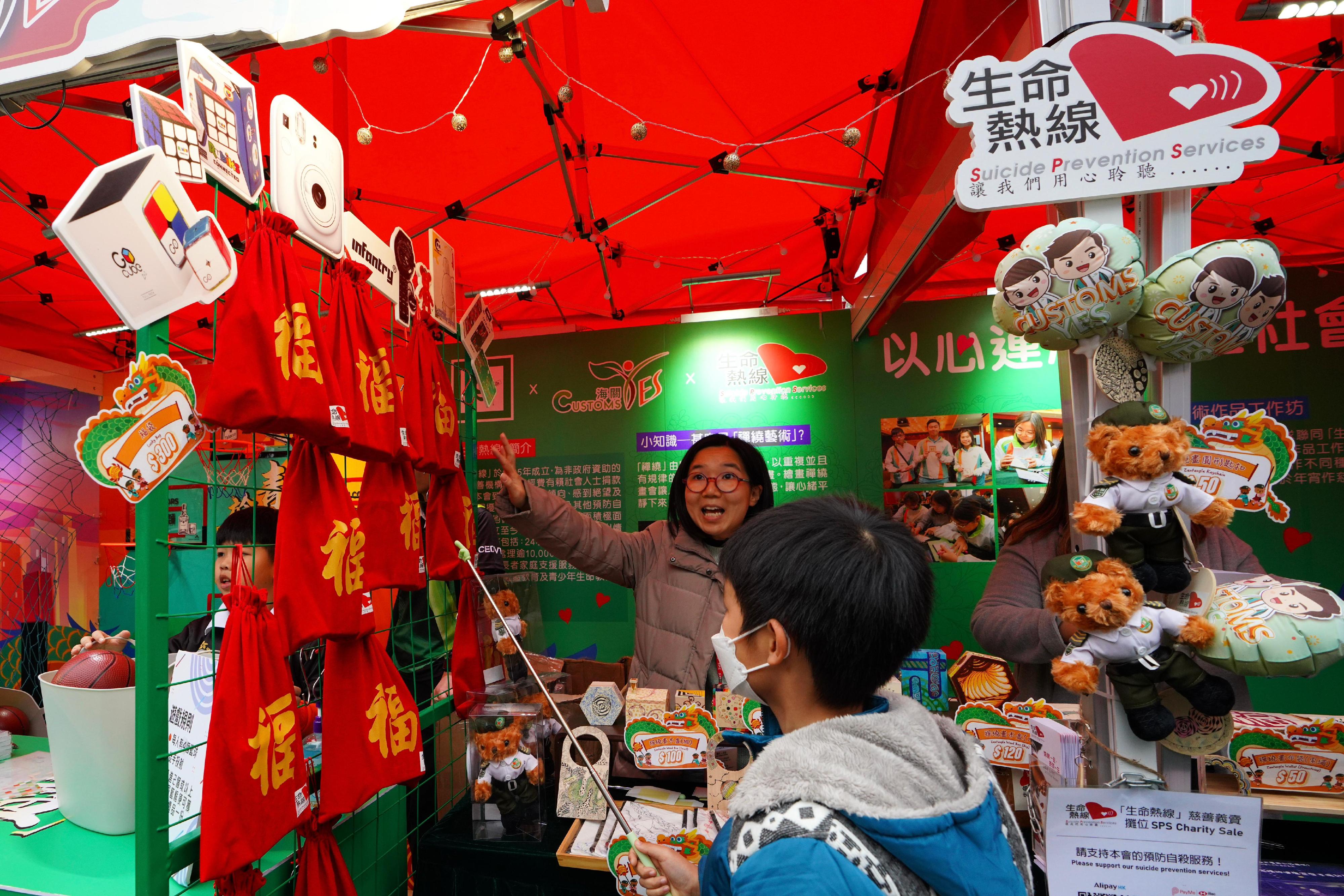 香港海關在二月七日至九日於維多利亞公園年宵市場設置以「海關繽FUN慶龍年」為題的新春年宵攤位，並與社福機構「生命熱線」攜手舉辦年宵慈善義賣。圖示於攤位售賣的「海關青年領袖團」熊公仔、禪繞藝術品和由各界善長捐贈物品組成的新春福袋。