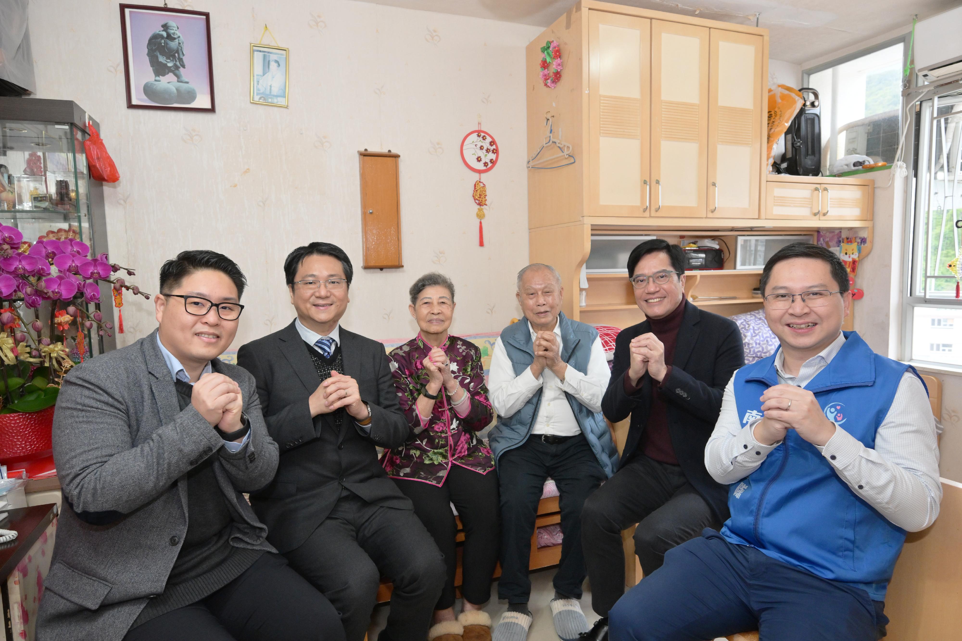 The Deputy Financial Secretary, Mr Michael Wong (second right), accompanied by the District Officer (Southern), Mr Francis Cheng (second left), with Southern District Council member Mr Pang Siu-kei (first left) and representative of Care Team (Southern) Mr Roy Chu (first right), visit Mr and Mrs Sin (third right and third left) in Shek Pai Wan Estate, Southern District, today (February 8).