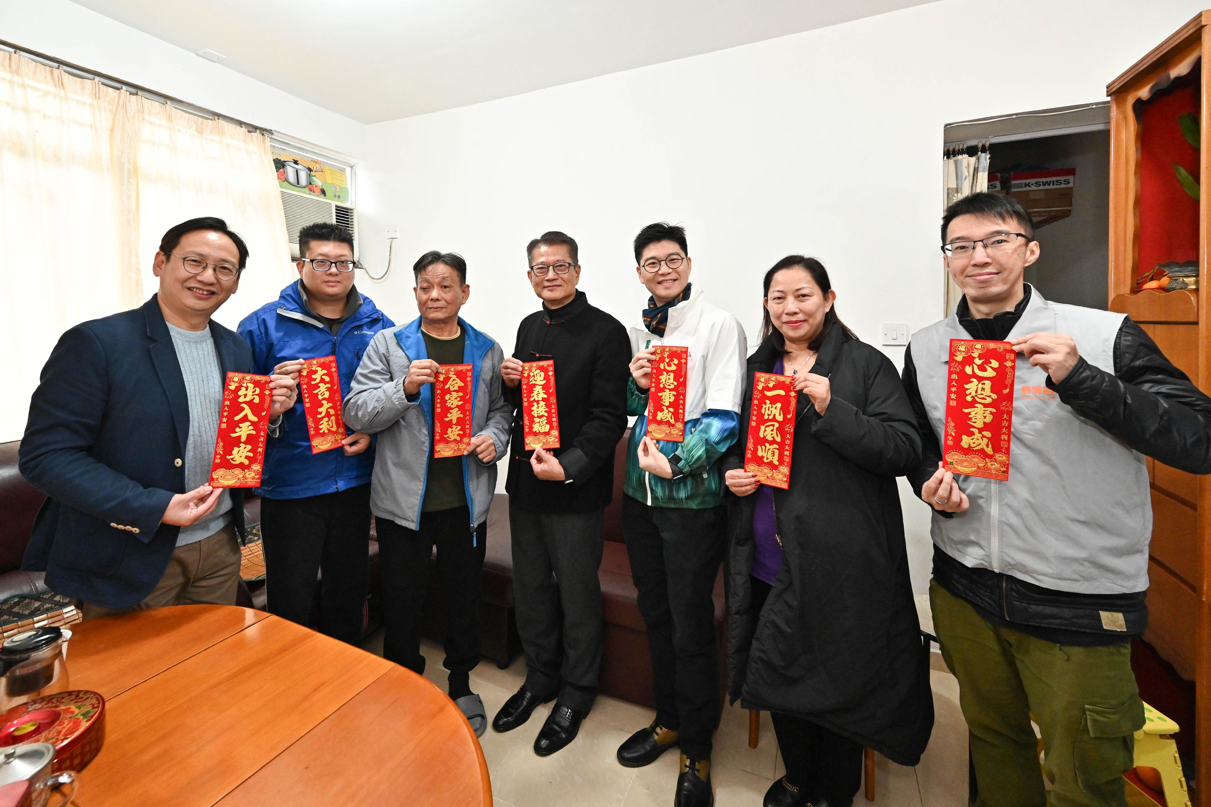 The Financial Secretary, Mr Paul Chan (centre), accompanied by the District Officer (Kwun Tong), Mr Denny Ho (third right), visits a family living in Tak Tin Estate, Lam Tin, today (February 9) to extend Chinese New Year blessings.