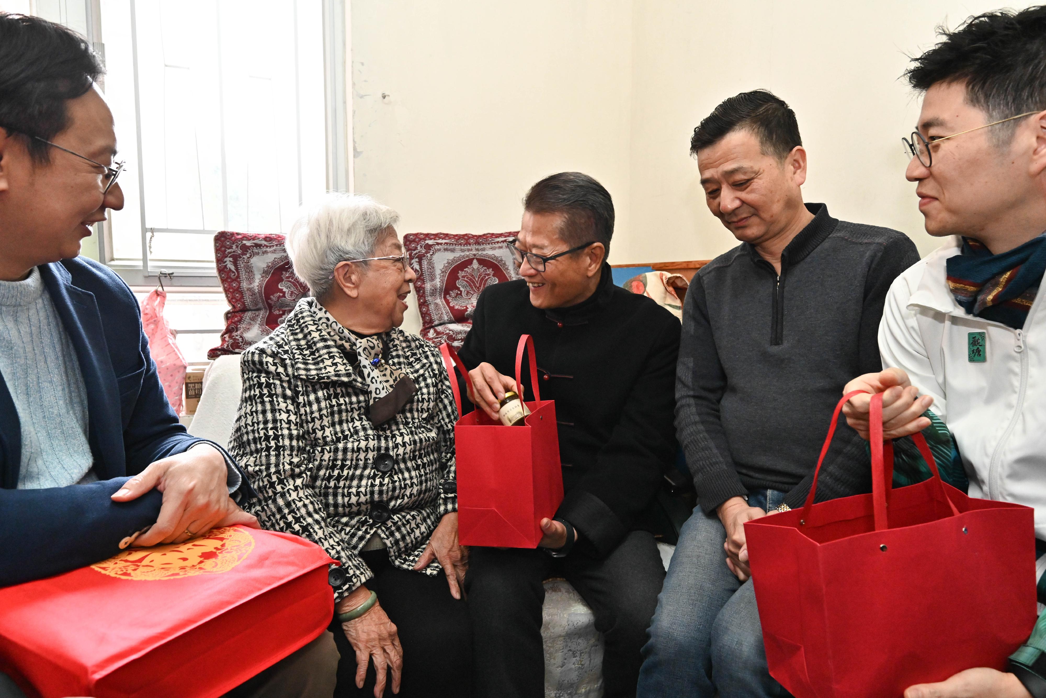 The Financial Secretary, Mr Paul Chan (centre), accompanied by the District Officer (Kwun Tong), Mr Denny Ho (first right), visits elderly people living in Tak Tin Estate, Lam Tin, today (February 9) and gives blessing bags to them.