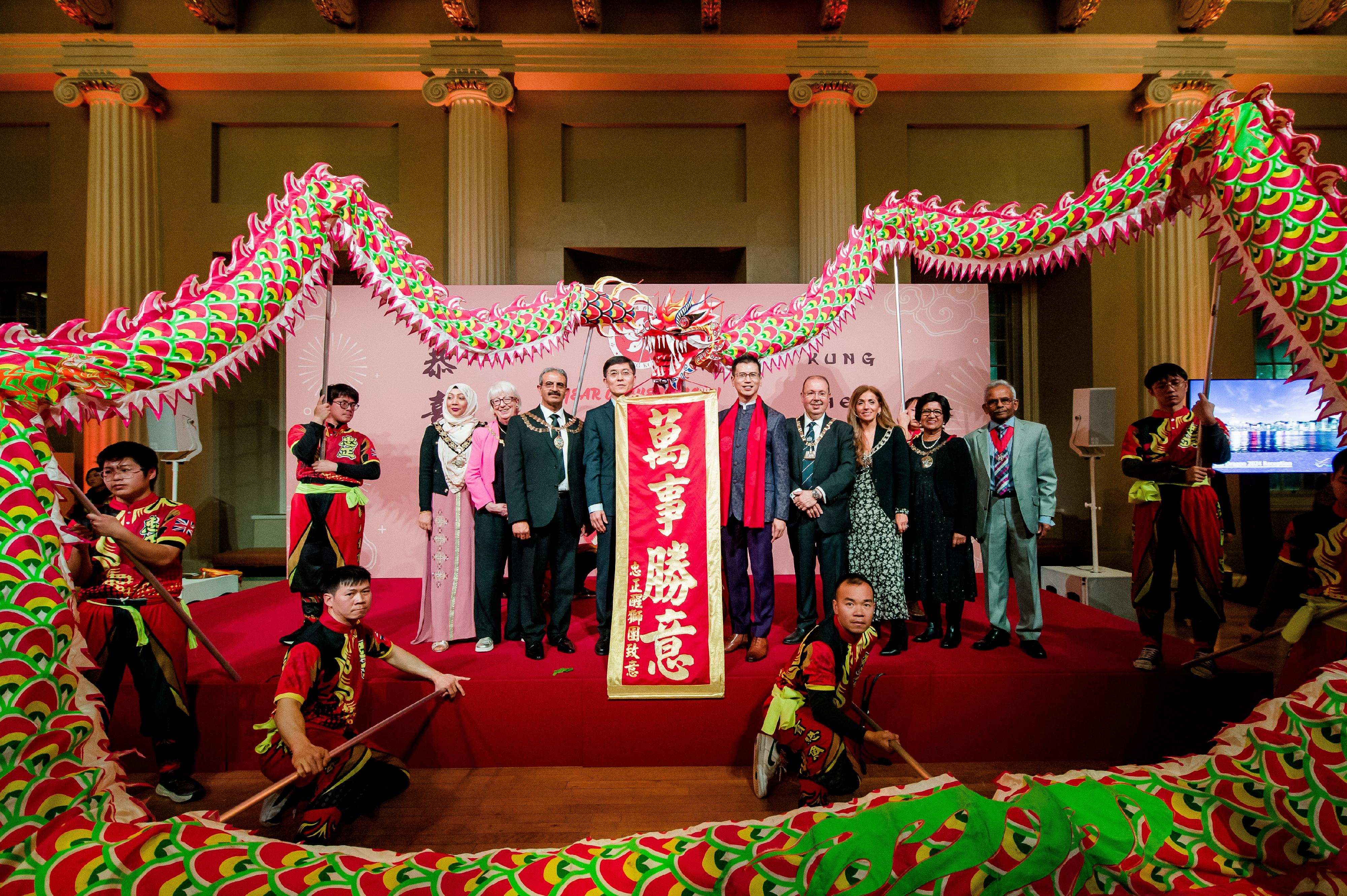 The Hong Kong Economic and Trade Office, London (London ETO) greeted the Year of the Dragon in the United Kingdom by hosting a celebratory reception at Banqueting House, Whitehall, in London on February 13 (London time). Photo shows the Director-General of the London ETO, Mr Gilford Law (fifth right), and Minister and First Staff Member, Embassy of the People's Republic of China in the UK, Mr Yang Xiaoguang (sixth right), and some guests with the dragon dance team at the reception.