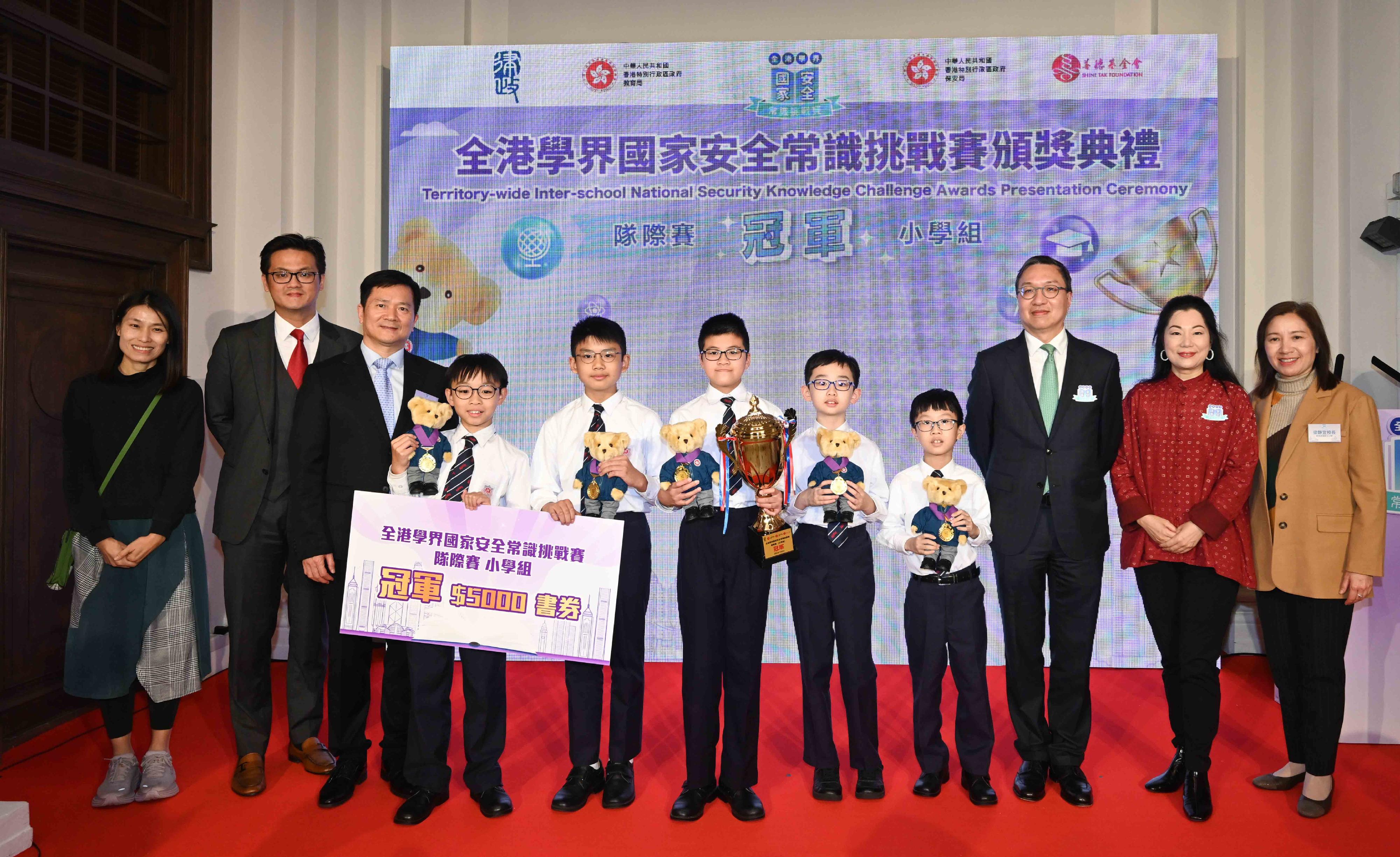 The Territory-wide Inter-school National Security Knowledge Challenge, jointly organised by the Department of Justice, the Security Bureau, the Education Bureau and the Hong Kong Shine Tak Foundation, held its finals this morning (February 26), and a prize presentation ceremony at the former French Mission Building in the afternoon. Photo shows the Secretary for Justice, Mr Paul Lam, SC (third right); the Director General of the Police Liaison Department of the Liaison Office of the Central People's Government in the Hong Kong Special Administrative Region, Mr Chen Feng (third left); the Chairman of the Hong Kong Shine Tak Foundation, Mrs Tung Ng Ling-ling (second right); and other guests presenting the Champion award of primary school team competition to the participants from the Hennessy Road Government Primary School.